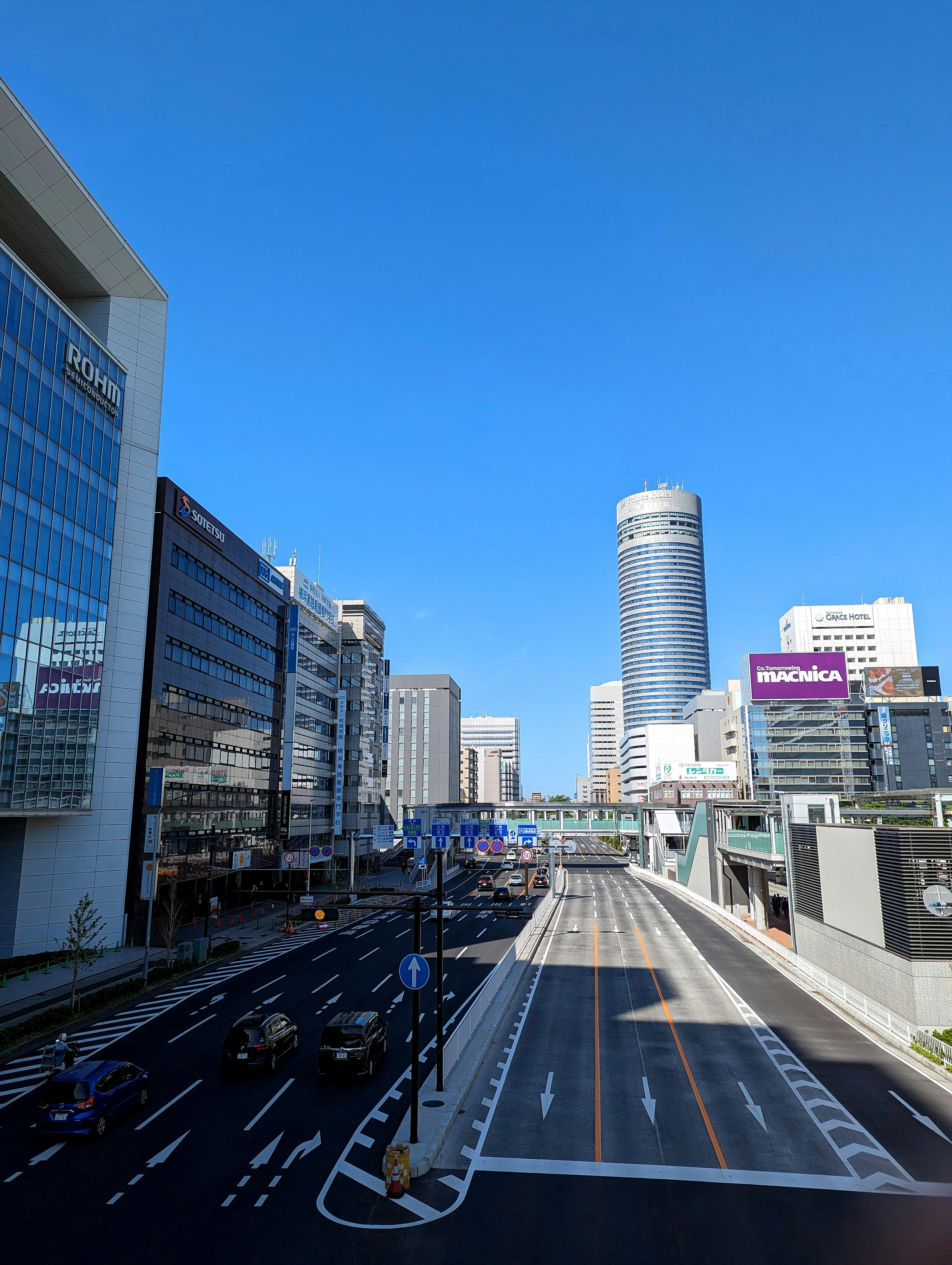 Urban landscape under blue sky featuring skyscrapers and wide road