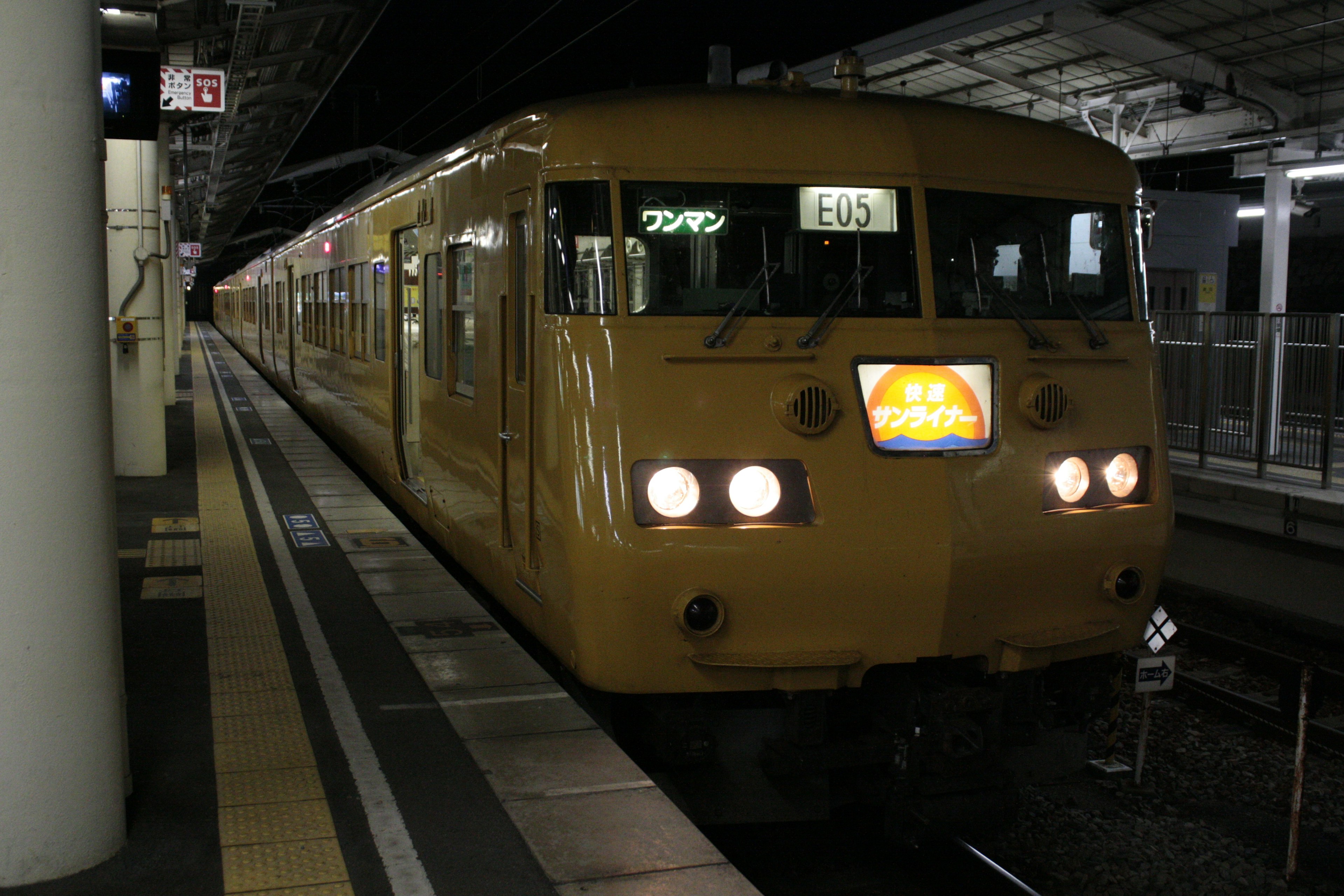 夜の駅に停車中の黄色い電車 車両の前面に明るいライトが点灯