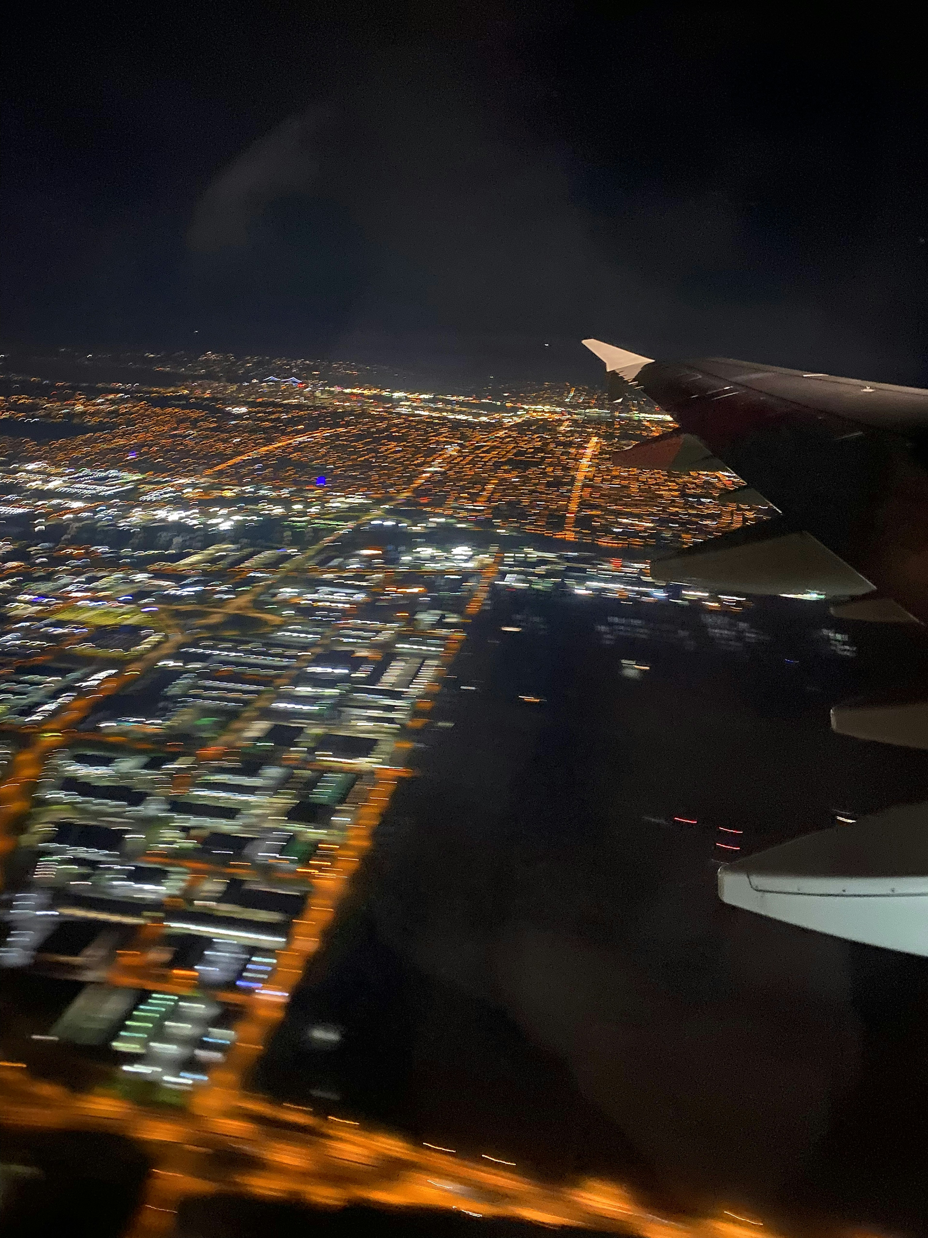 Vista aerea di una città di notte con l'ala di un aereo visibile