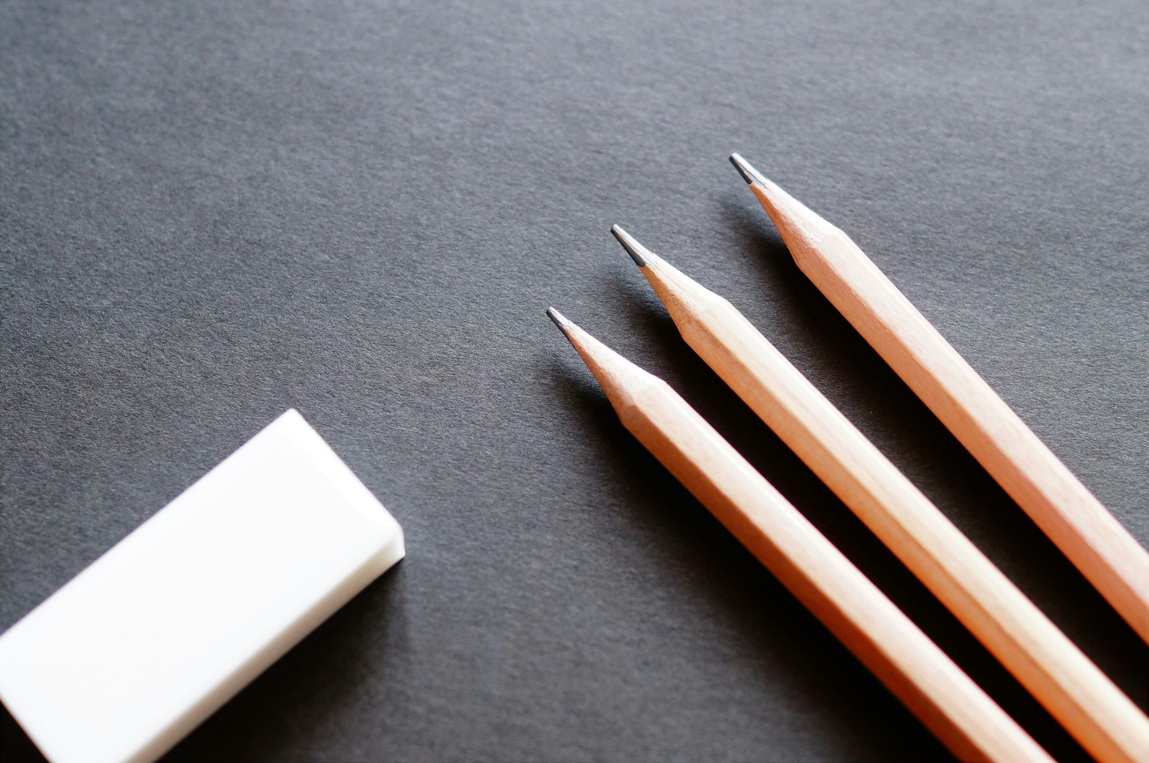 Tiga pensil dan penghapus putih di latar belakang hitam