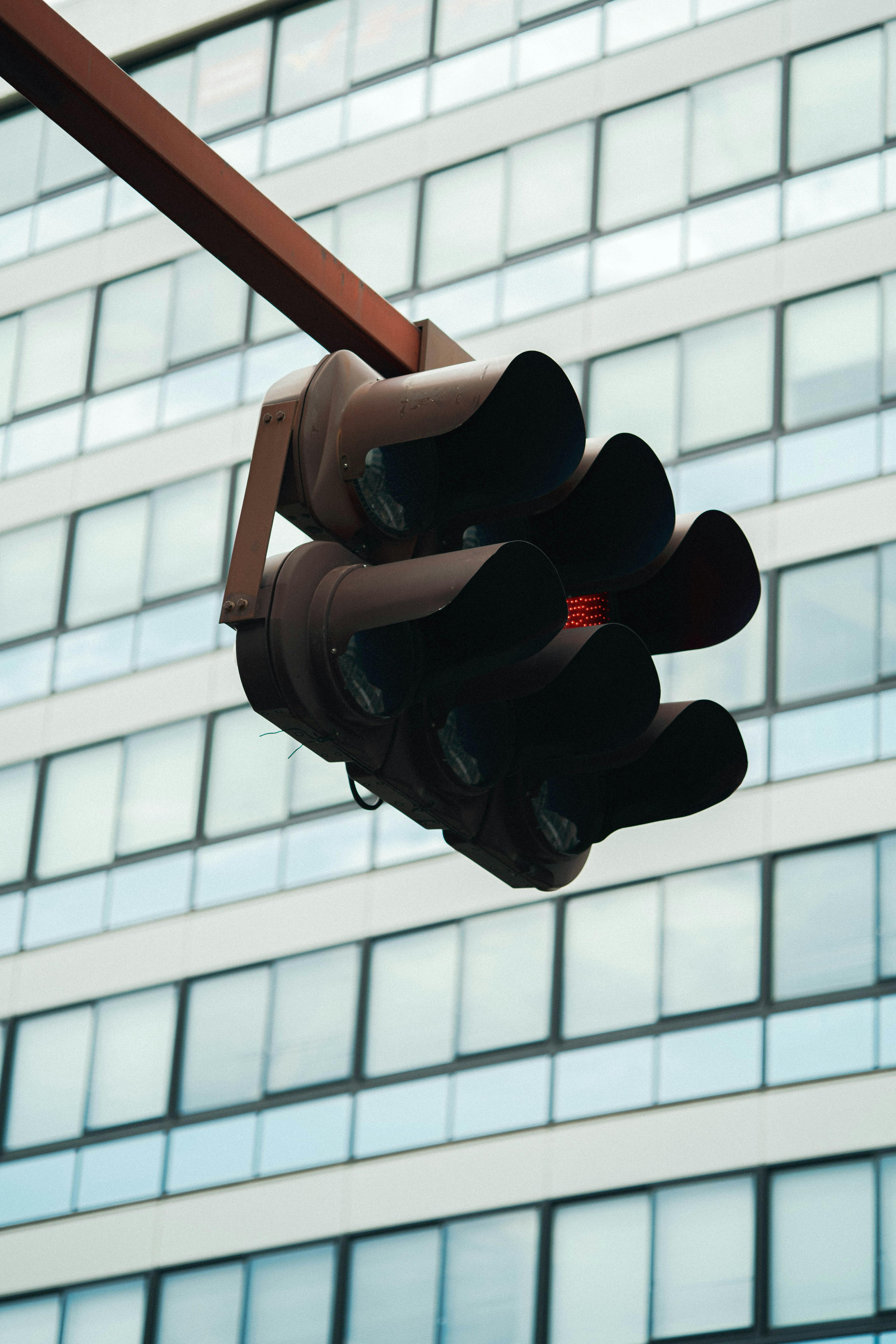 Traffic signal with red light in front of a modern building