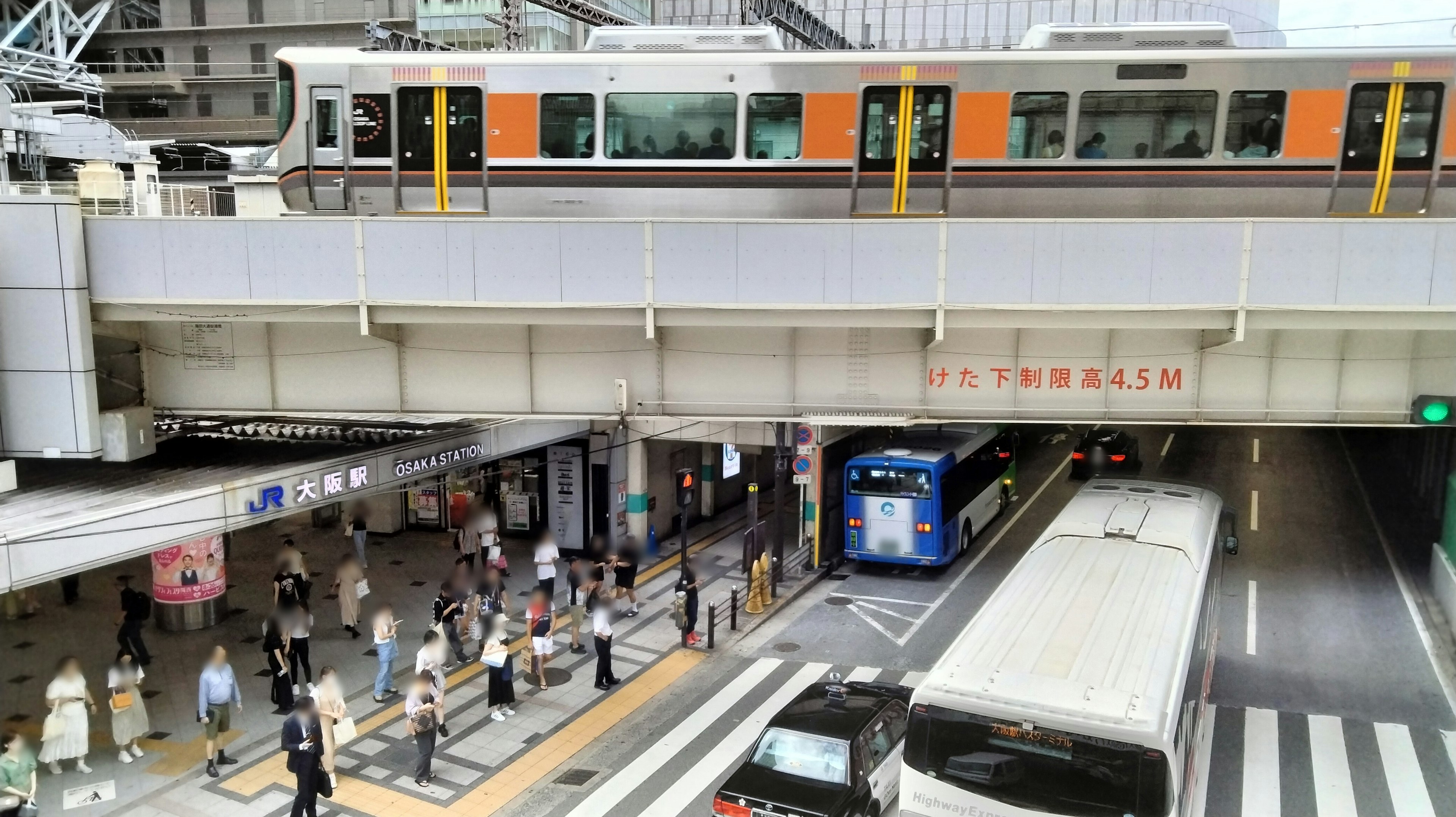 A bustling station scene with people and an overhead train