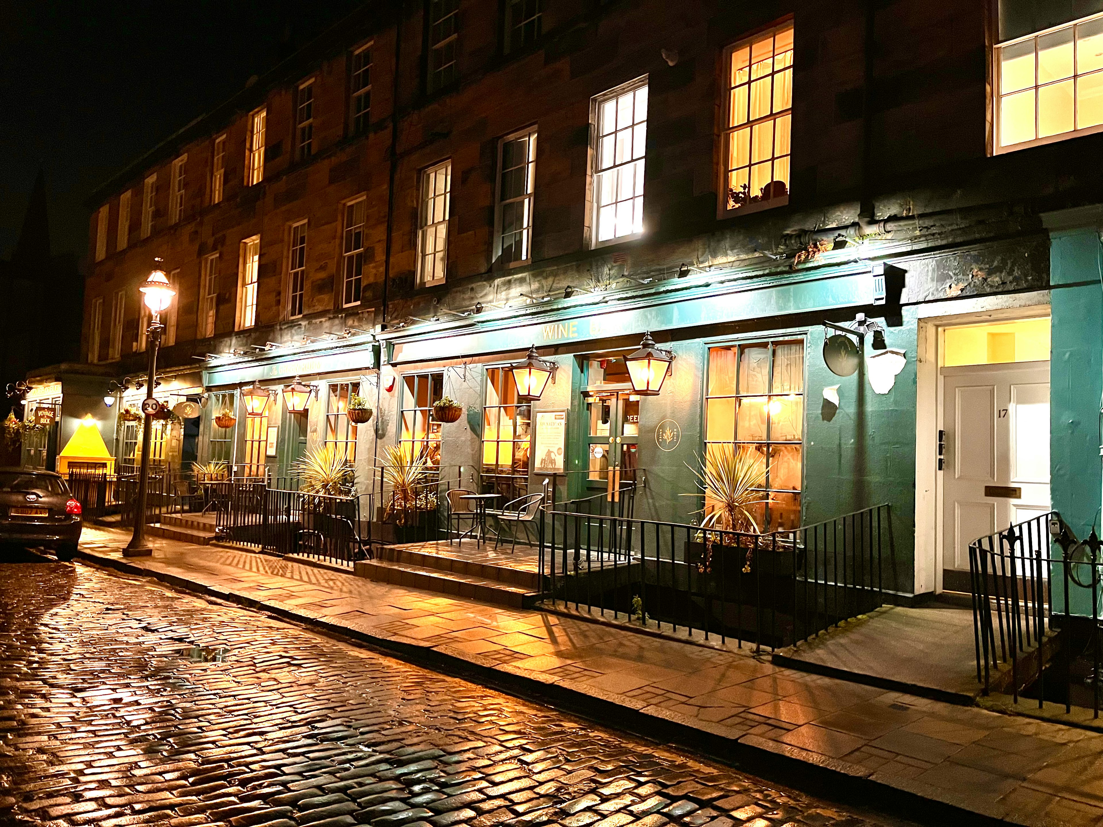 Illuminated café exterior at night with cobblestone street