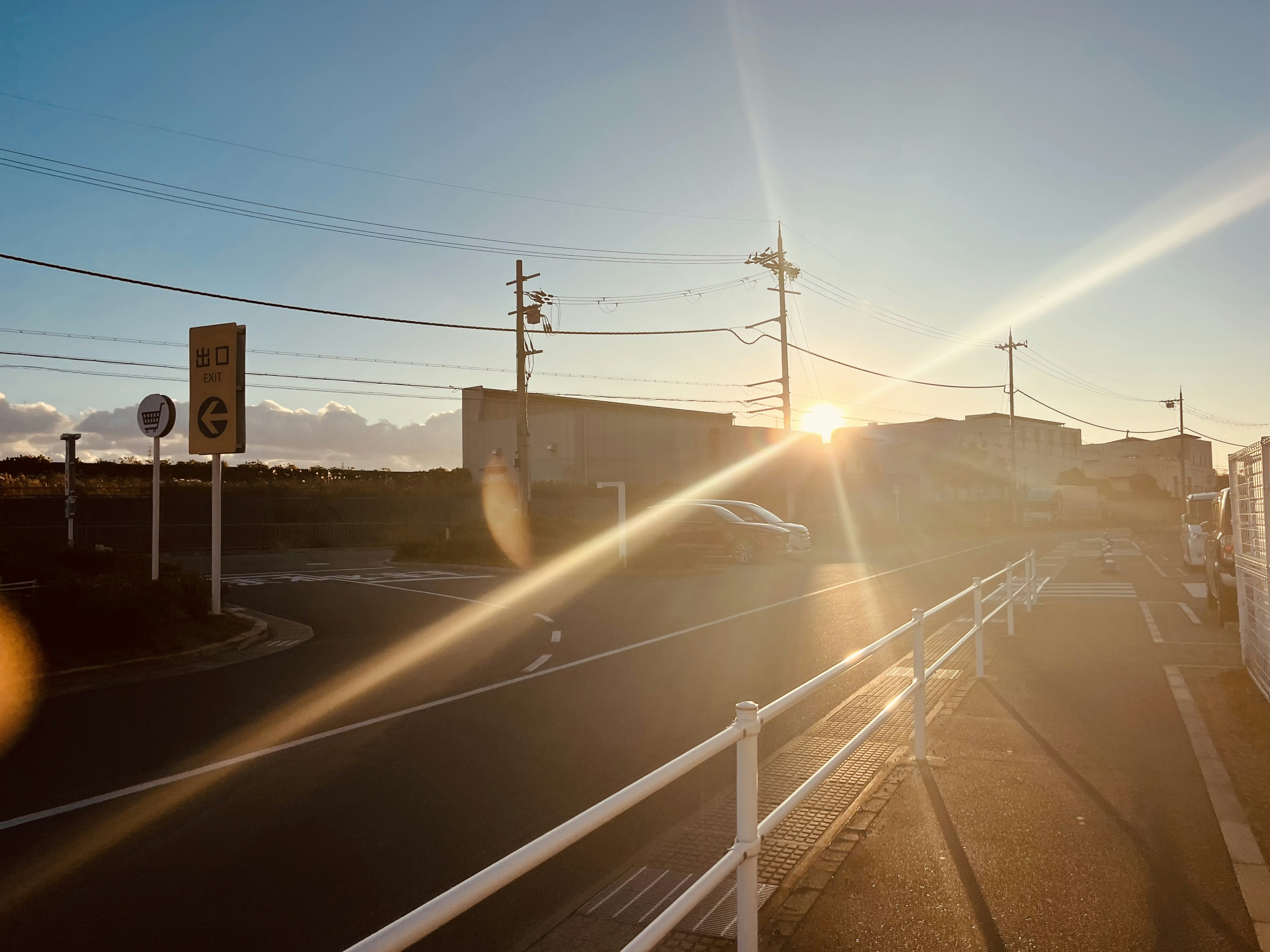 夕日が見える道路の風景 白いフェンスと標識がある