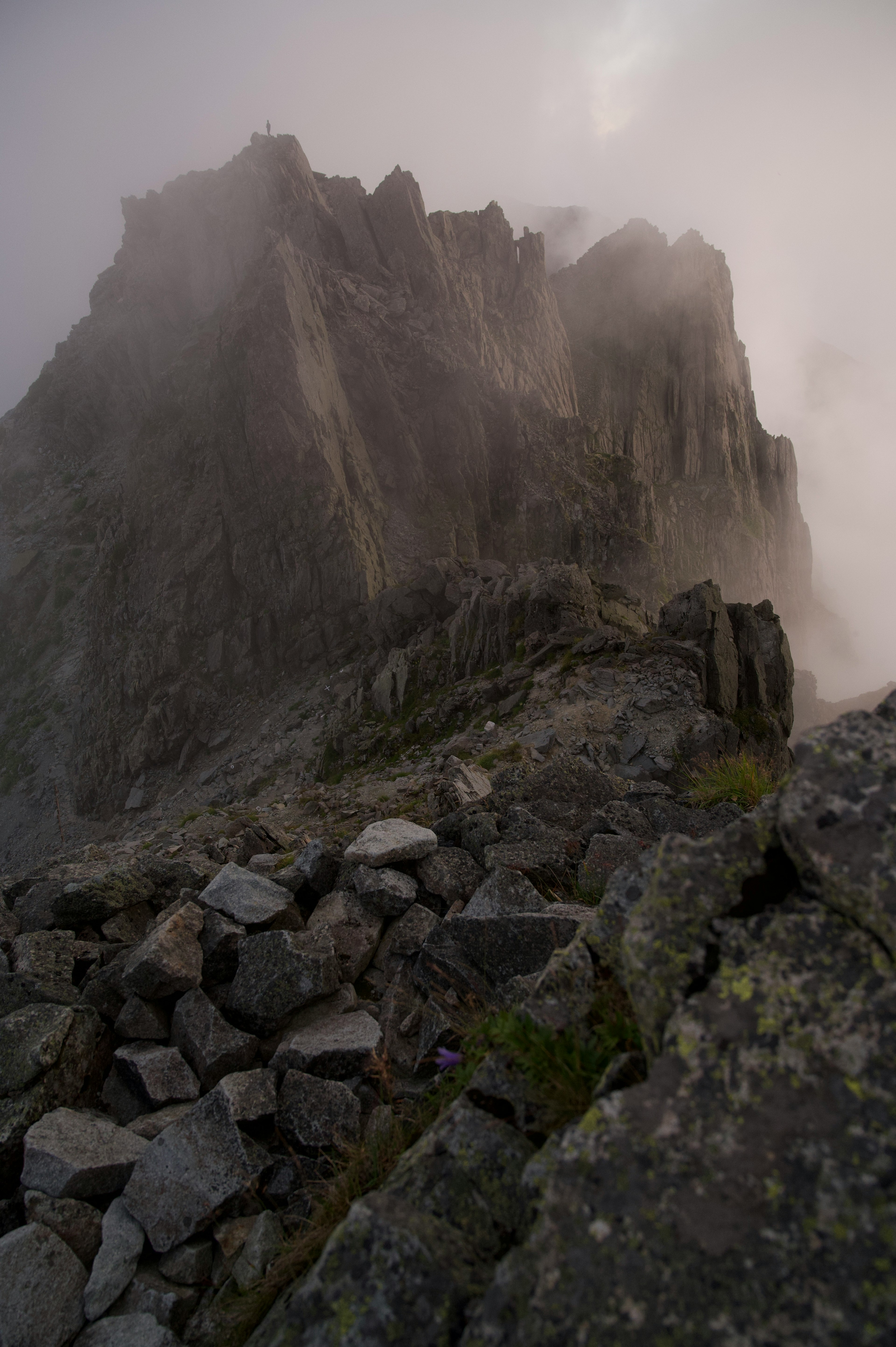 A mountain peak shrouded in fog with rocky terrain