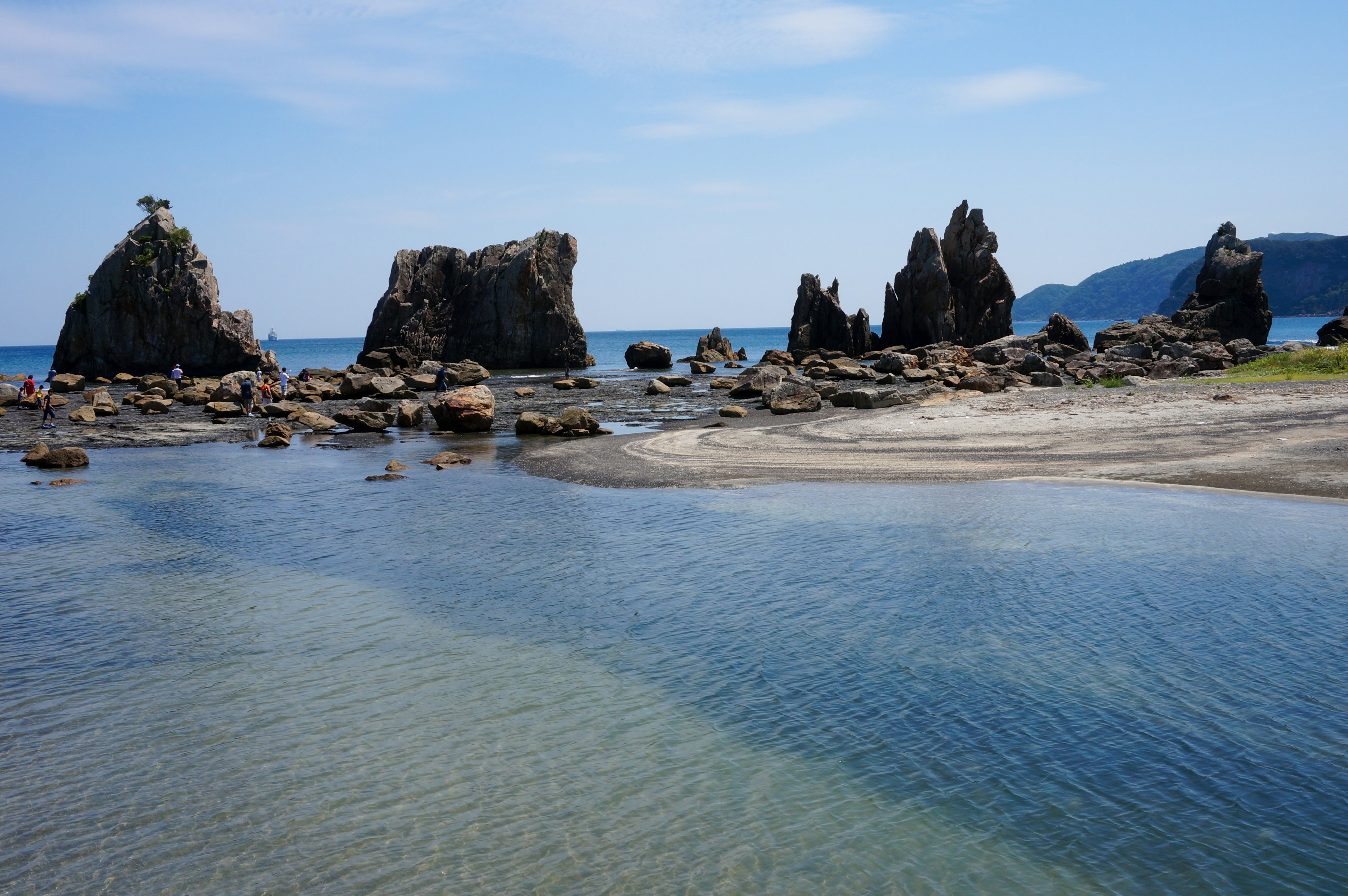 Beach scene featuring rocks and clear blue sea