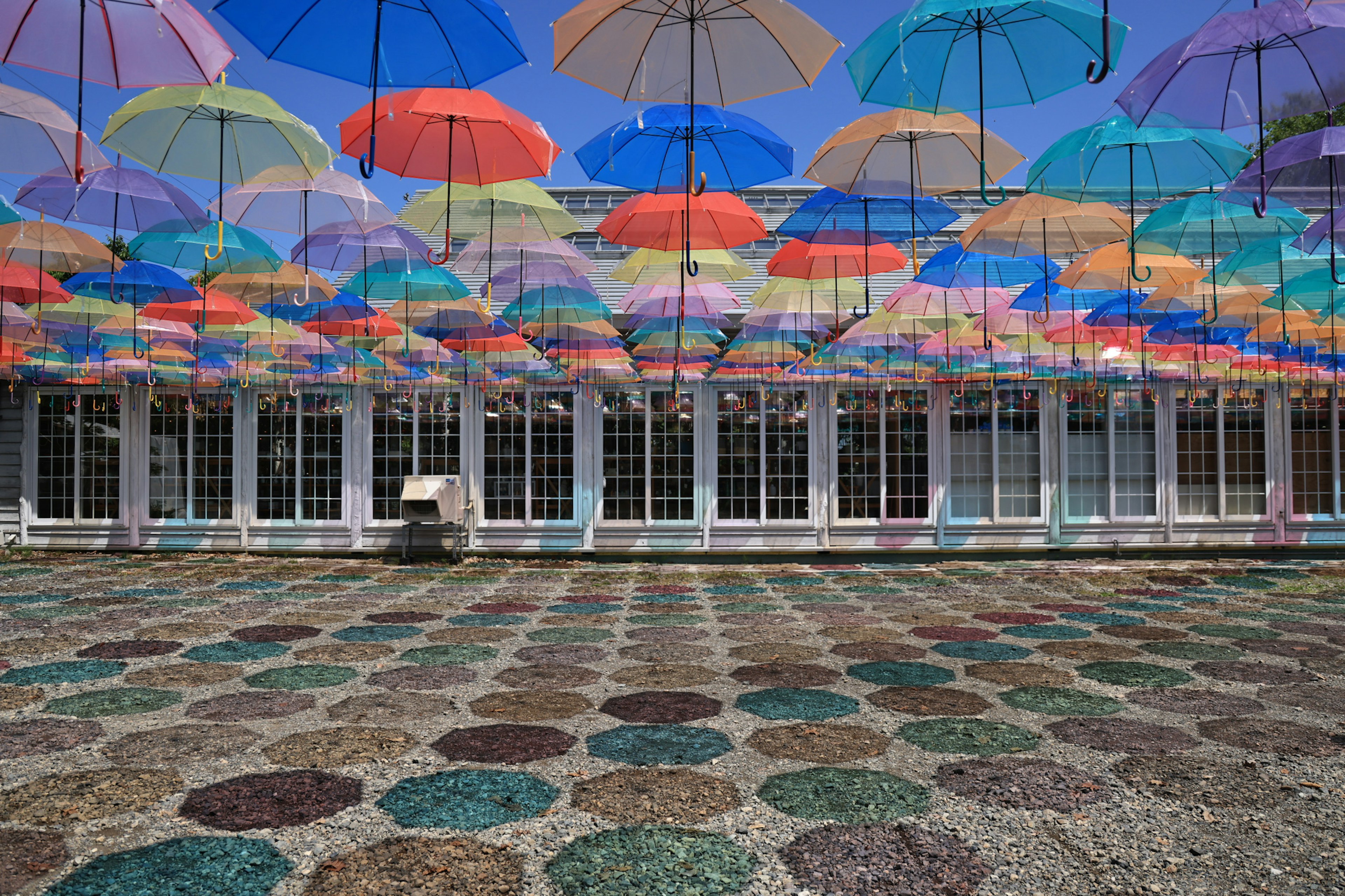 Sombrillas coloridas suspendidas sobre un suelo decorado en un espacio exterior