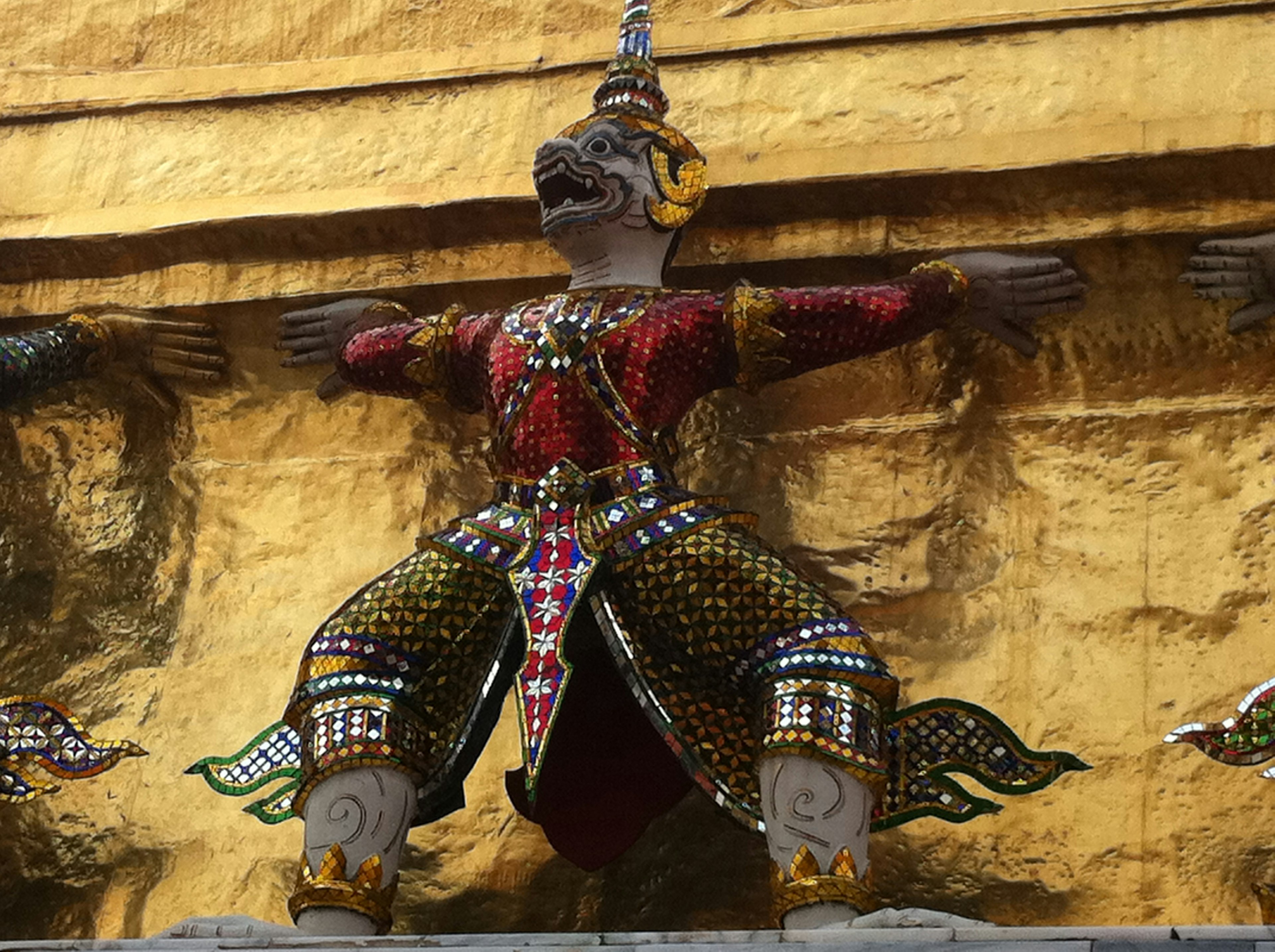 Dekorative Gottheit-Statue mit bunten Gewändern vor goldenem Hintergrund