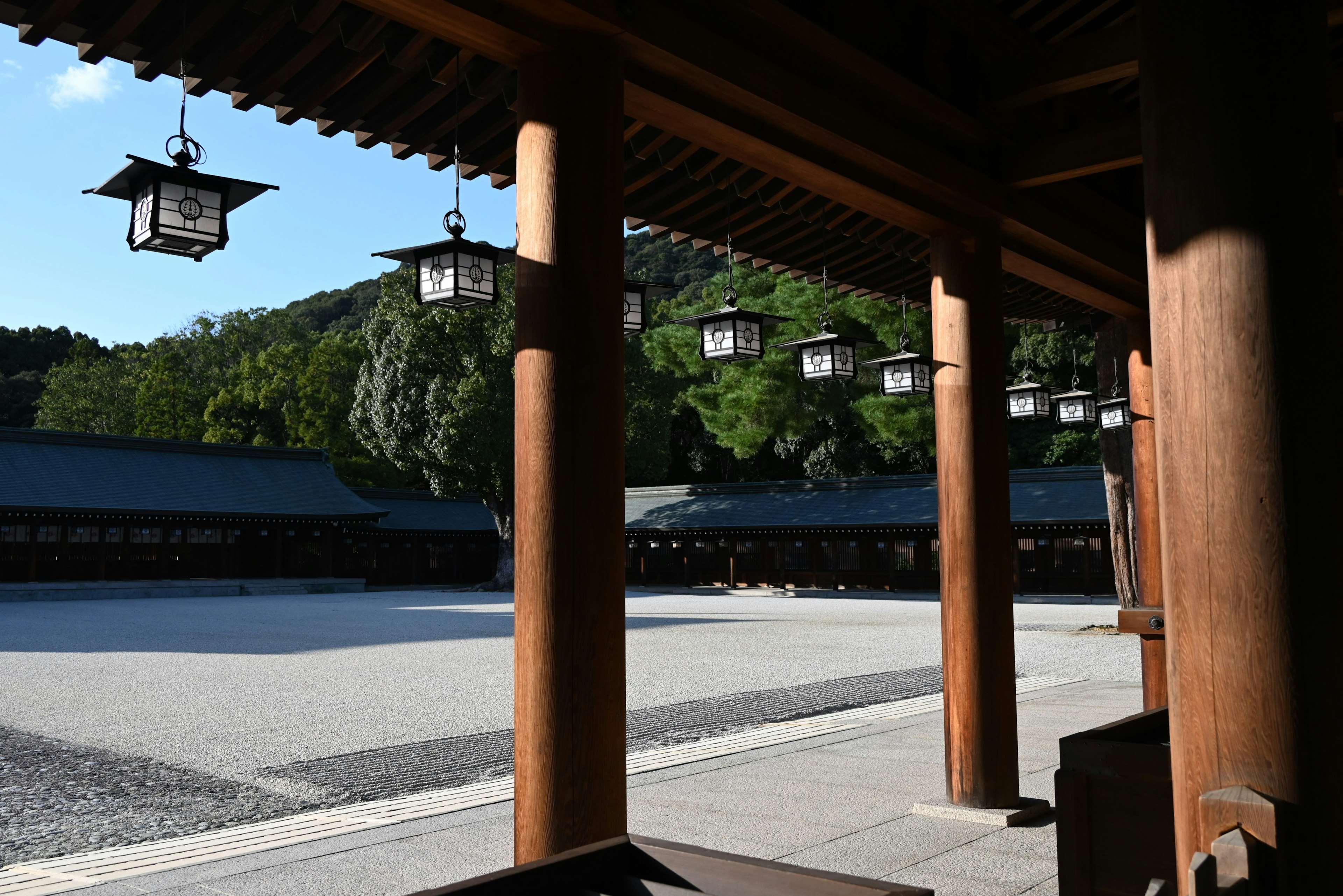 View of a serene shrine courtyard with wooden pillars and lanterns