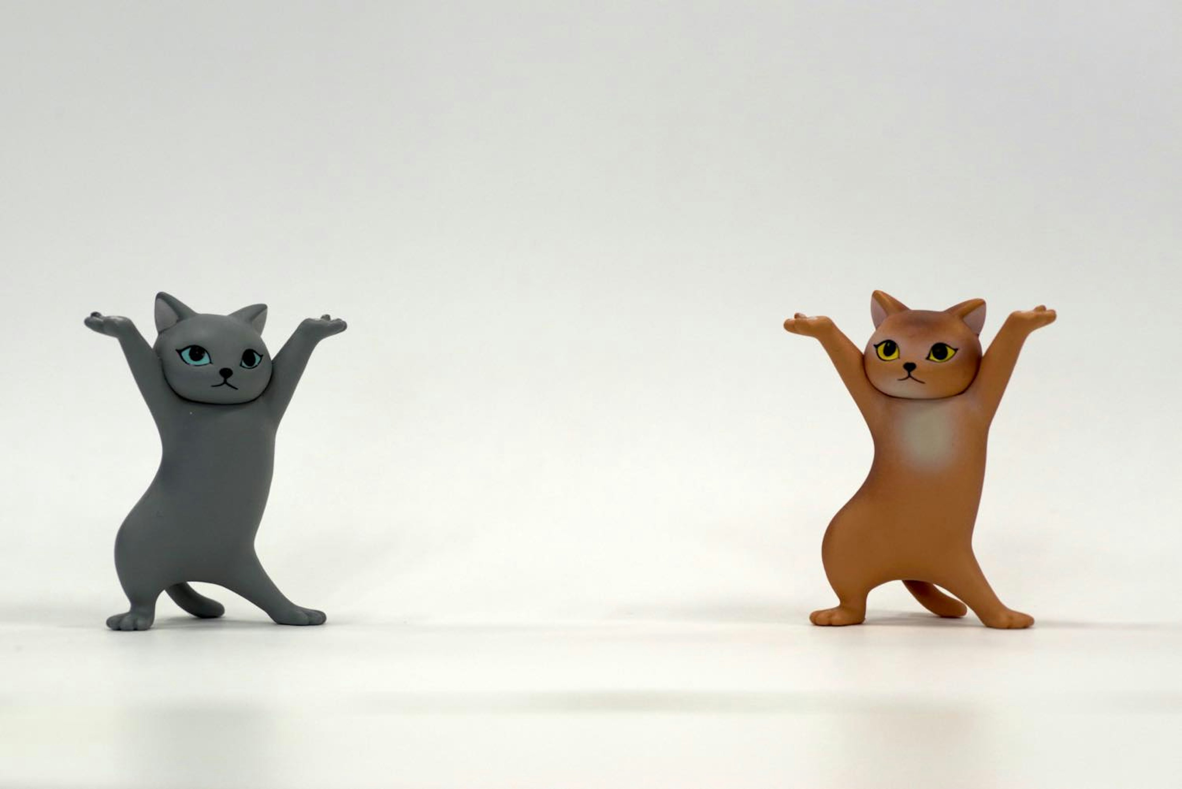 Two cat figurines standing with raised arms