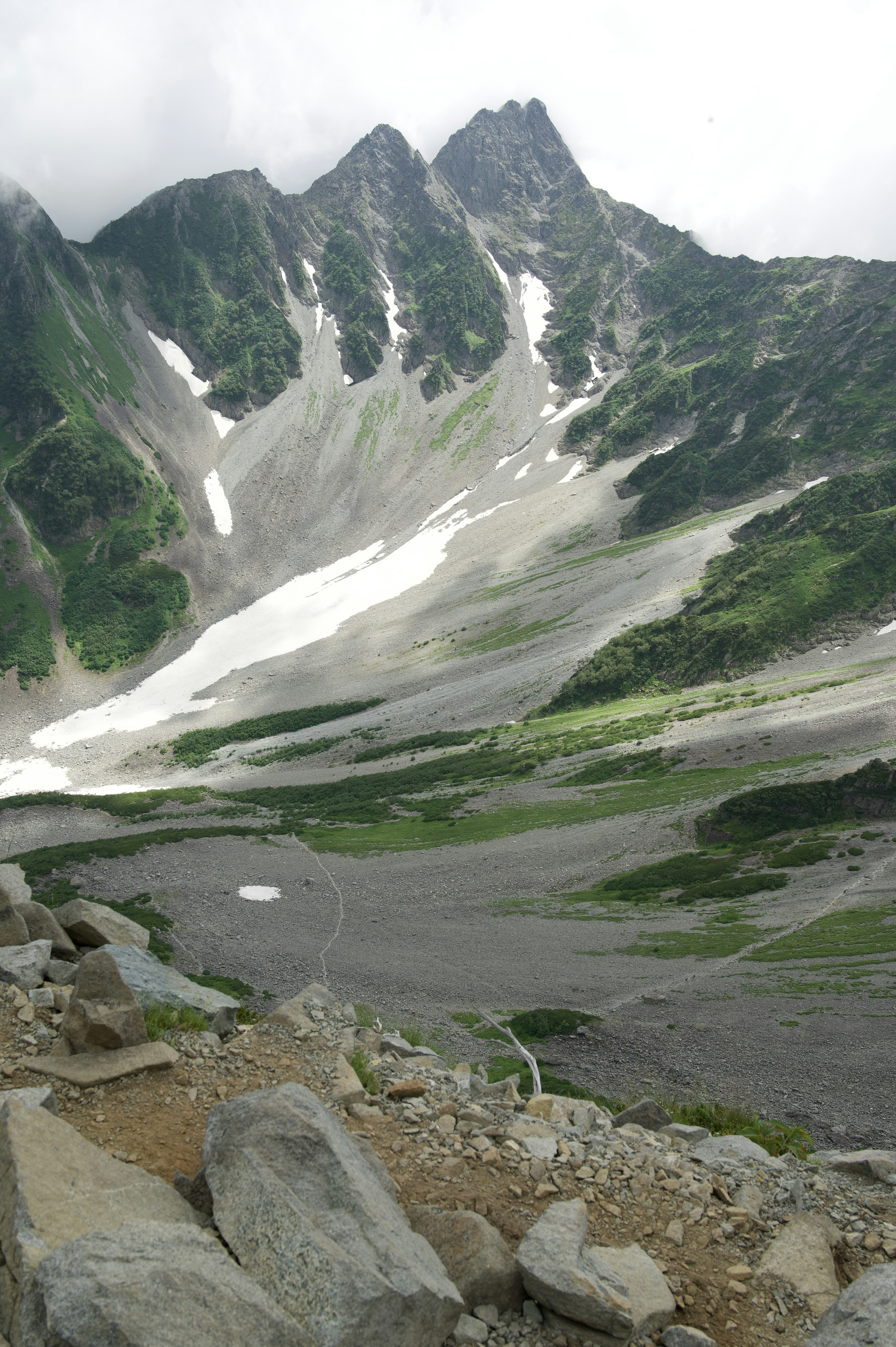 風景如畫的綠色山谷，山脈與斜坡上的殘雪