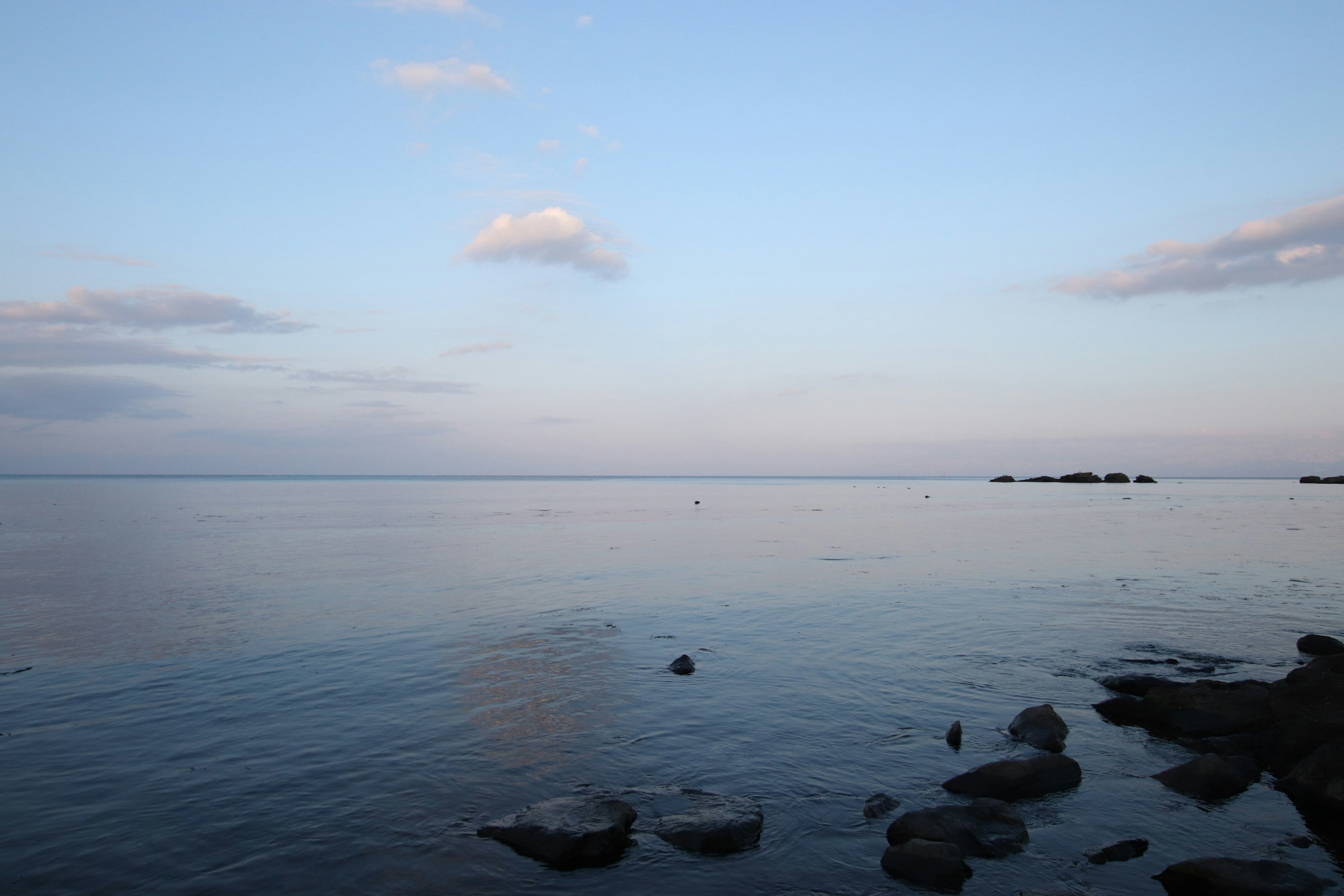 Mar tranquilo con cielo azul y nubes flotantes