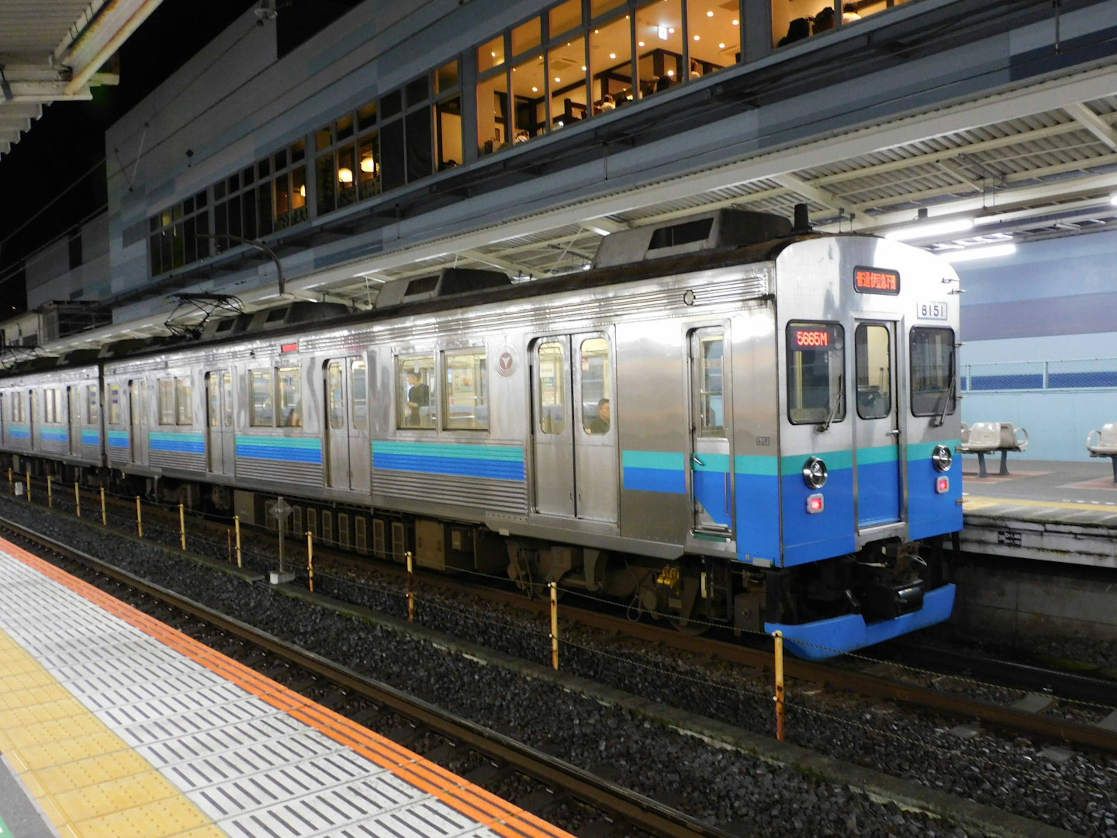 รถไฟสีน้ำเงินและสีเงินจอดที่สถานีในตอนกลางคืน