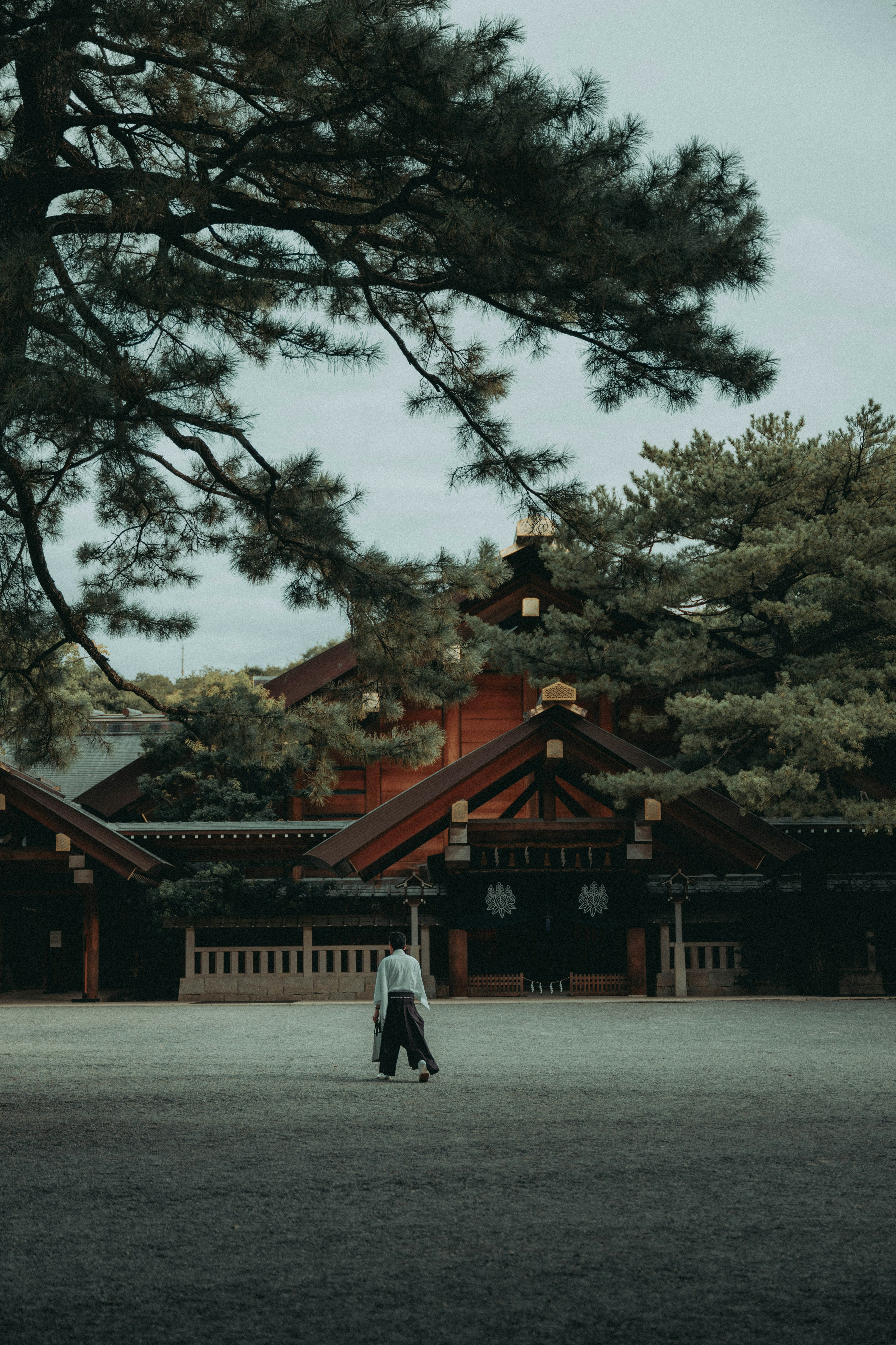 緑の木々に囲まれた伝統的な建物と散歩する人物