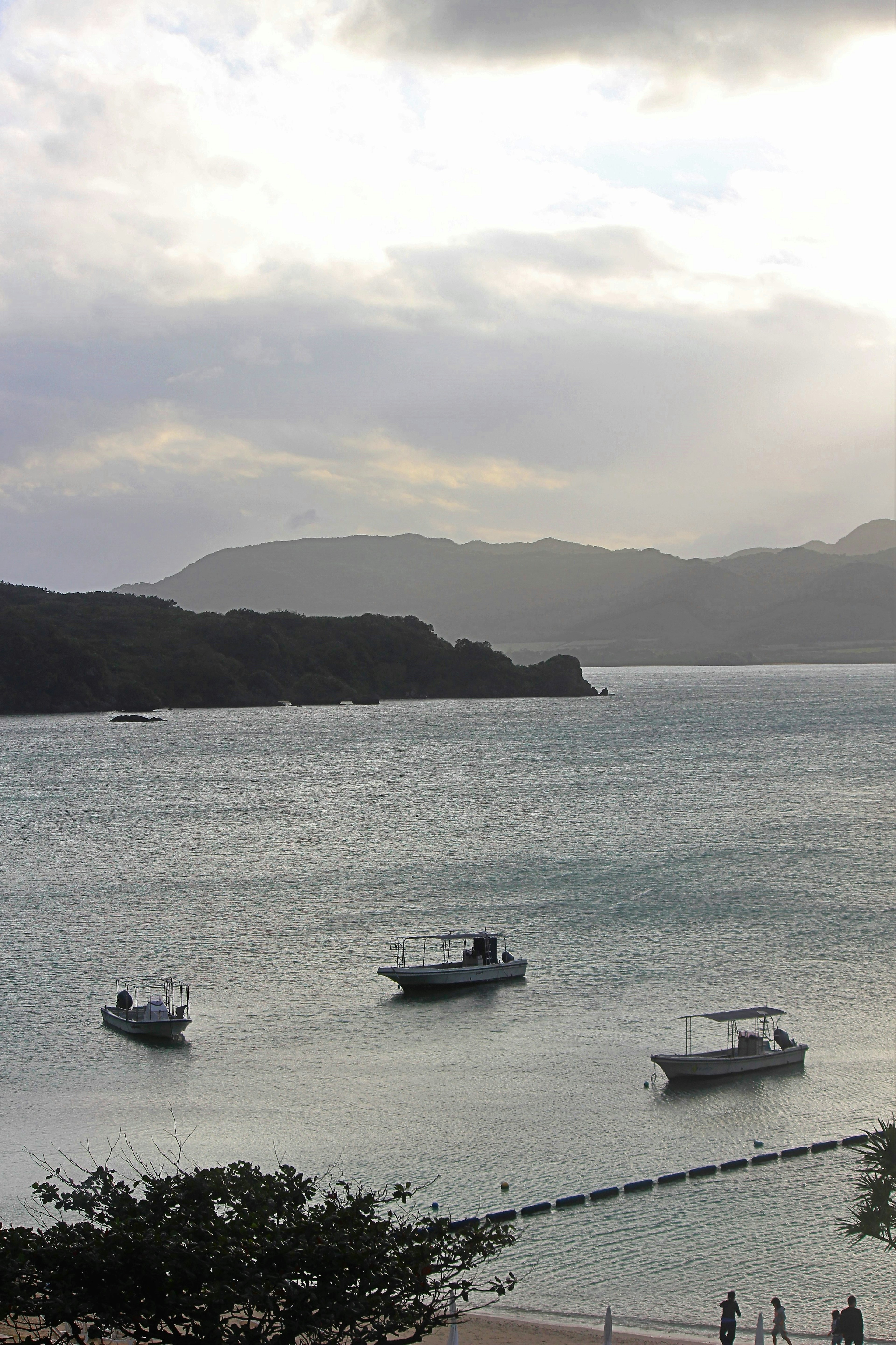 Boats floating on a calm sea with distant mountains