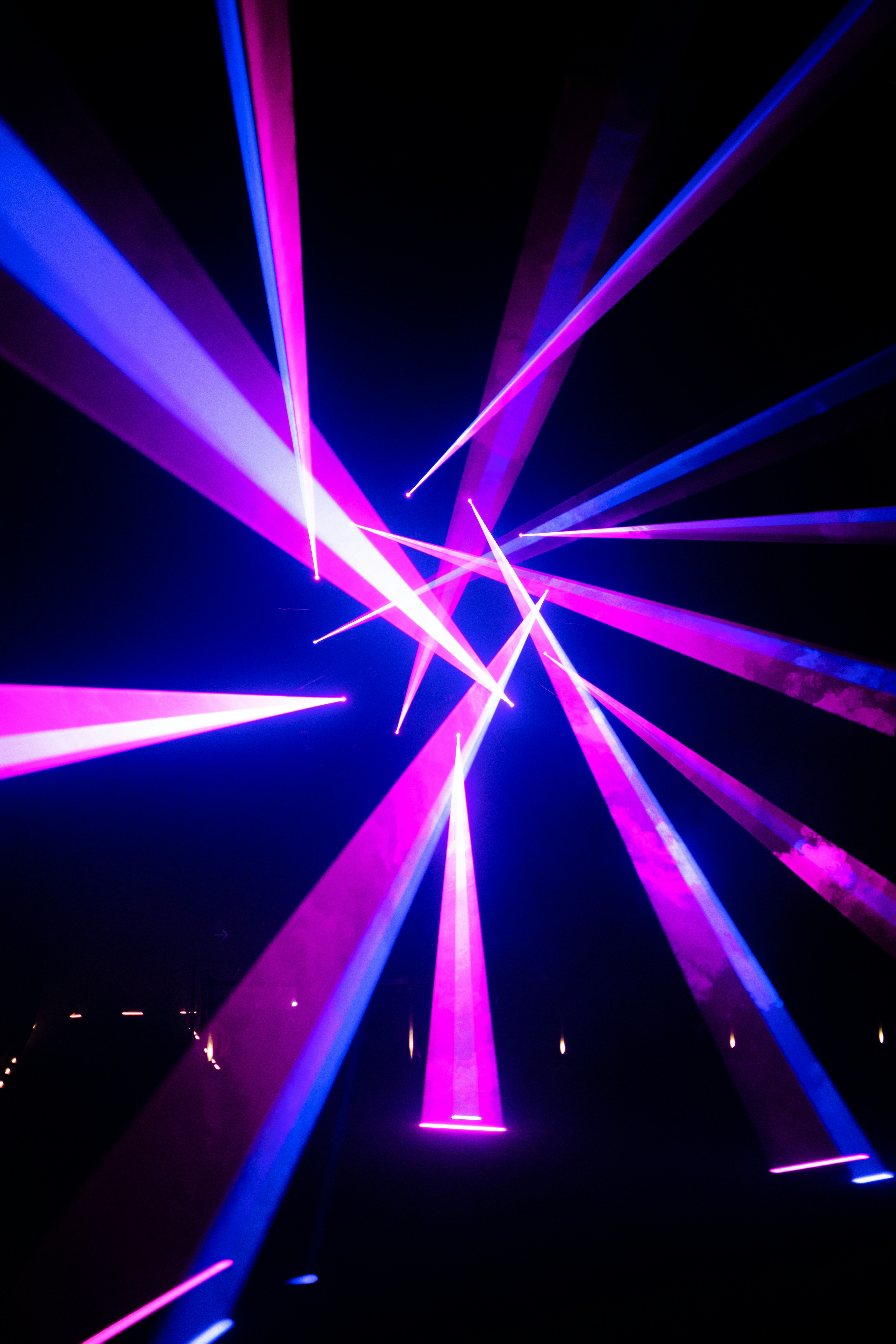 Vivid purple and blue laser beams intersecting against a dark background