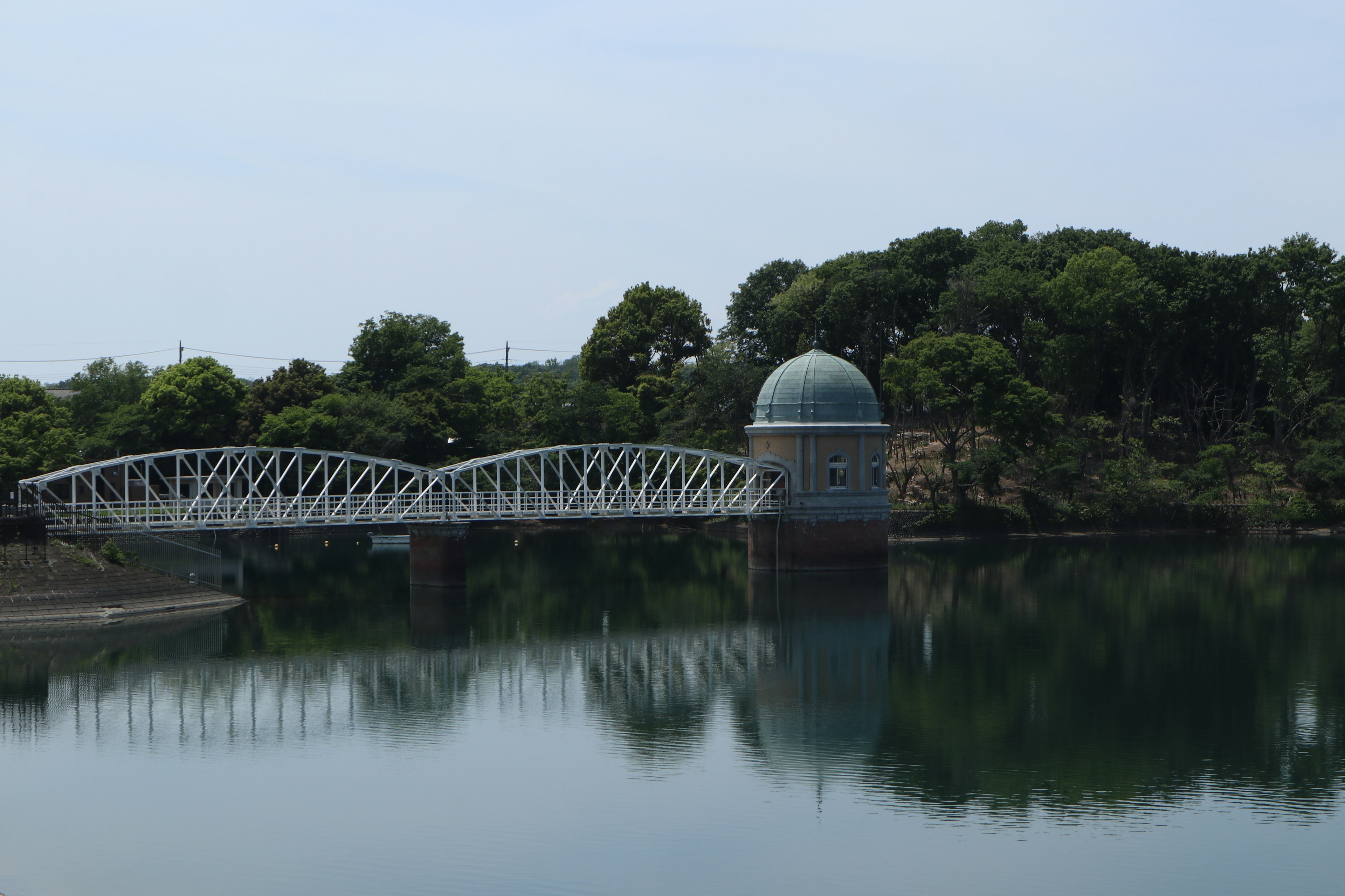 A white bridge and a dome-shaped building by a calm lake