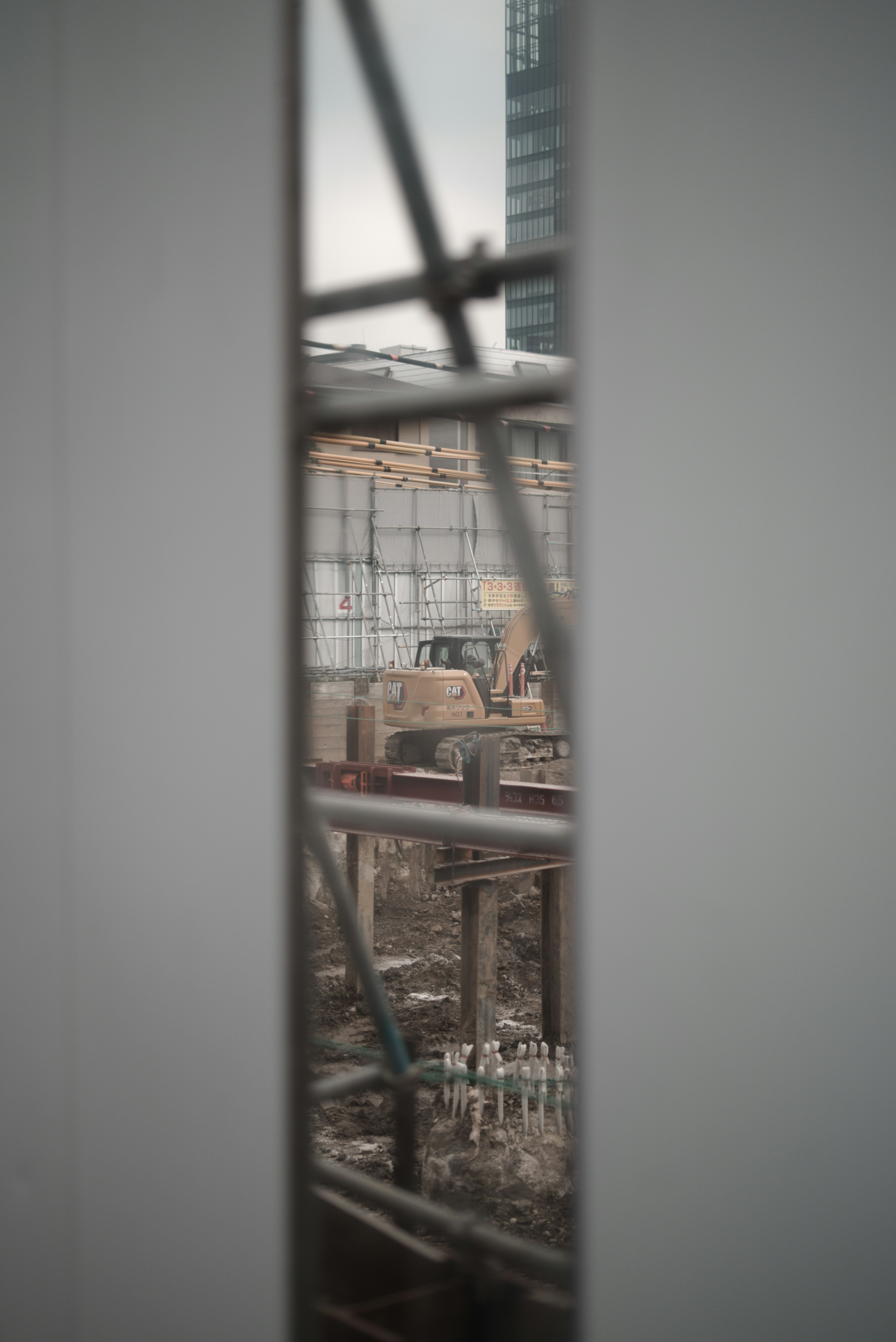 View through a window showing a construction site with steel framework