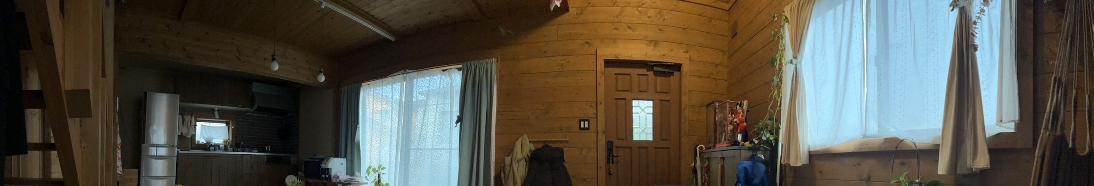 Interior de habitación de madera brillante con luz natural que entra por las ventanas cortinas y puerta visibles