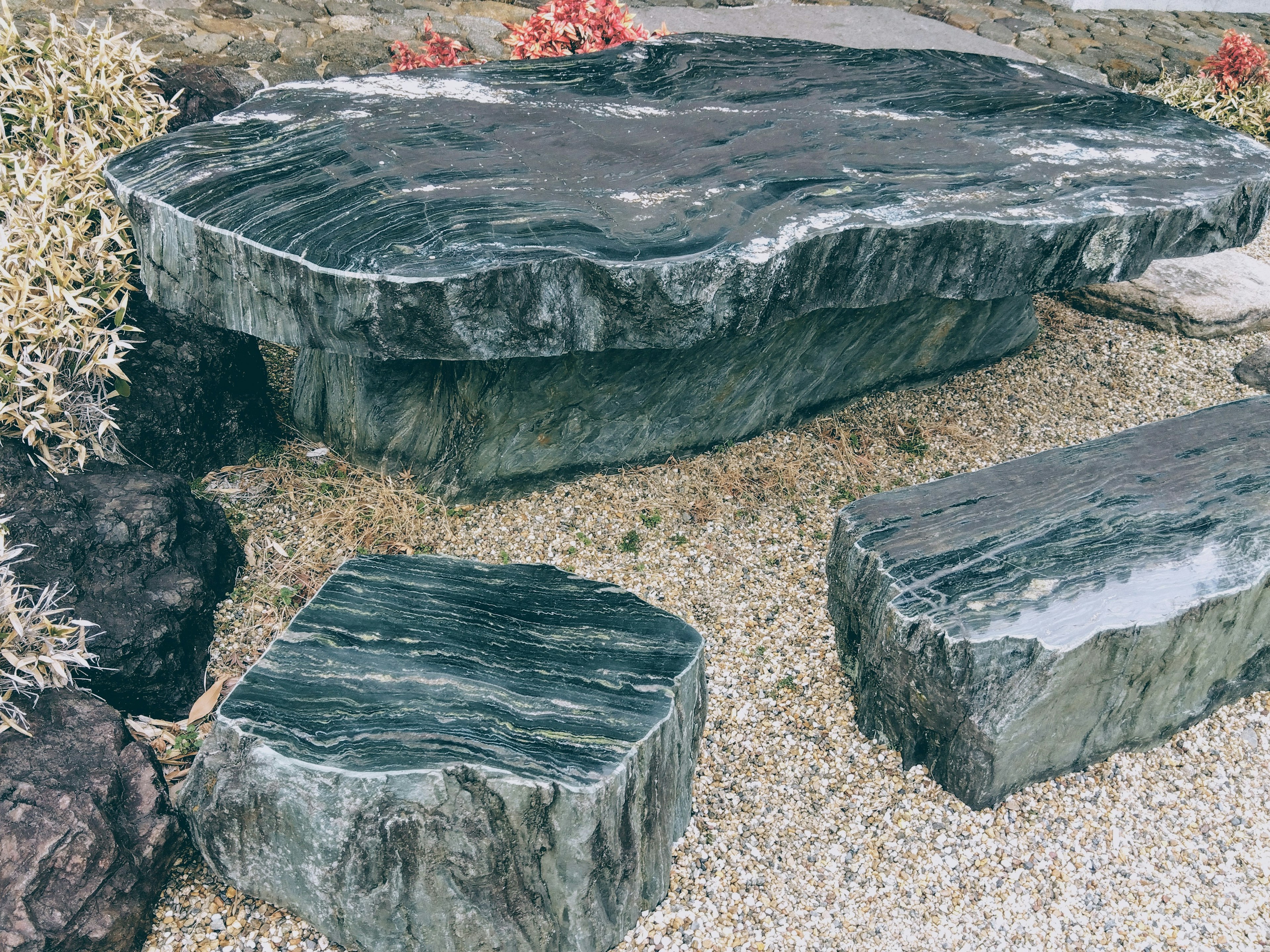 A set of garden furniture made of green stone including a table and benches