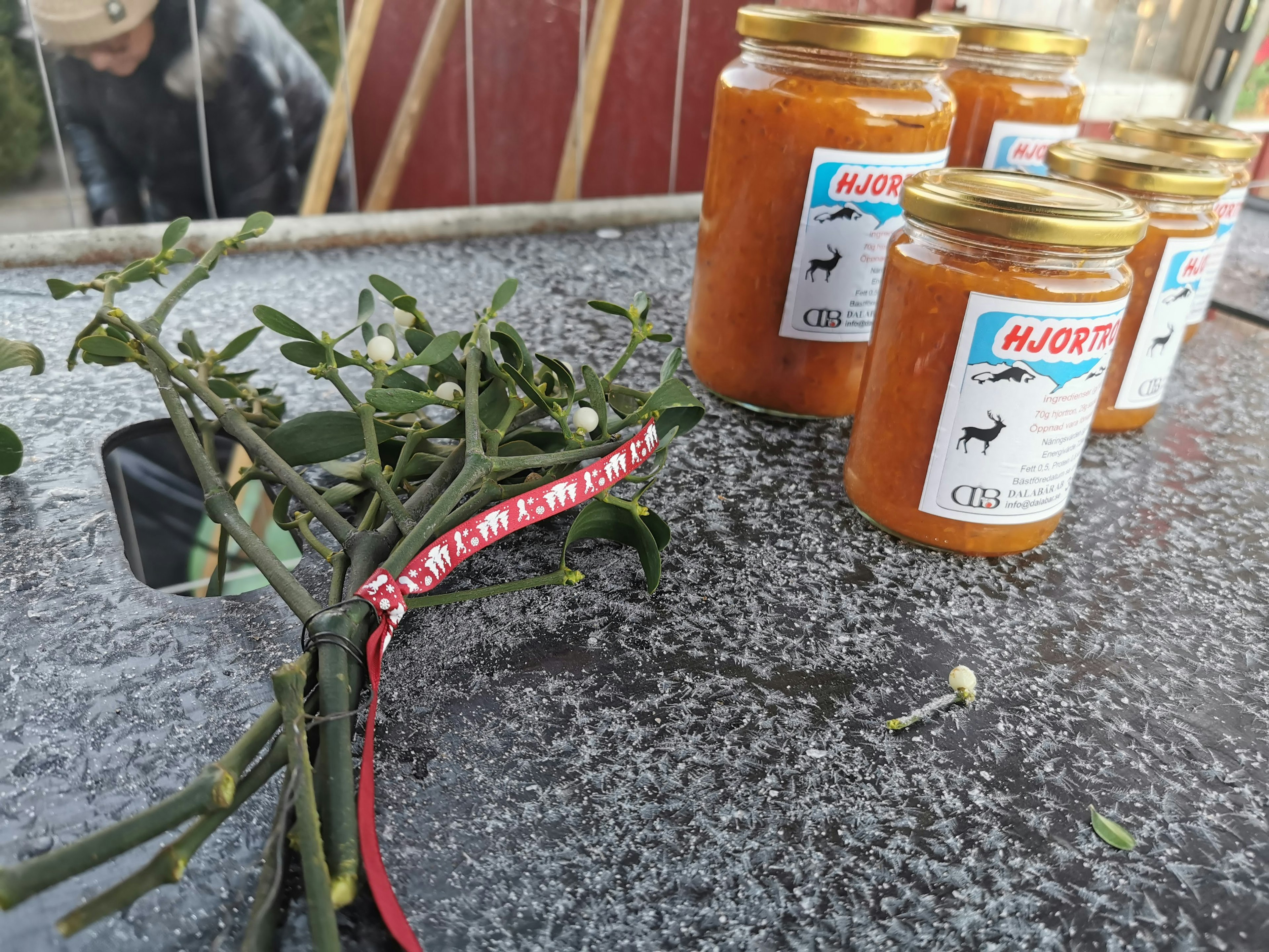 Jars of orange jam and a sprig of mistletoe on a table