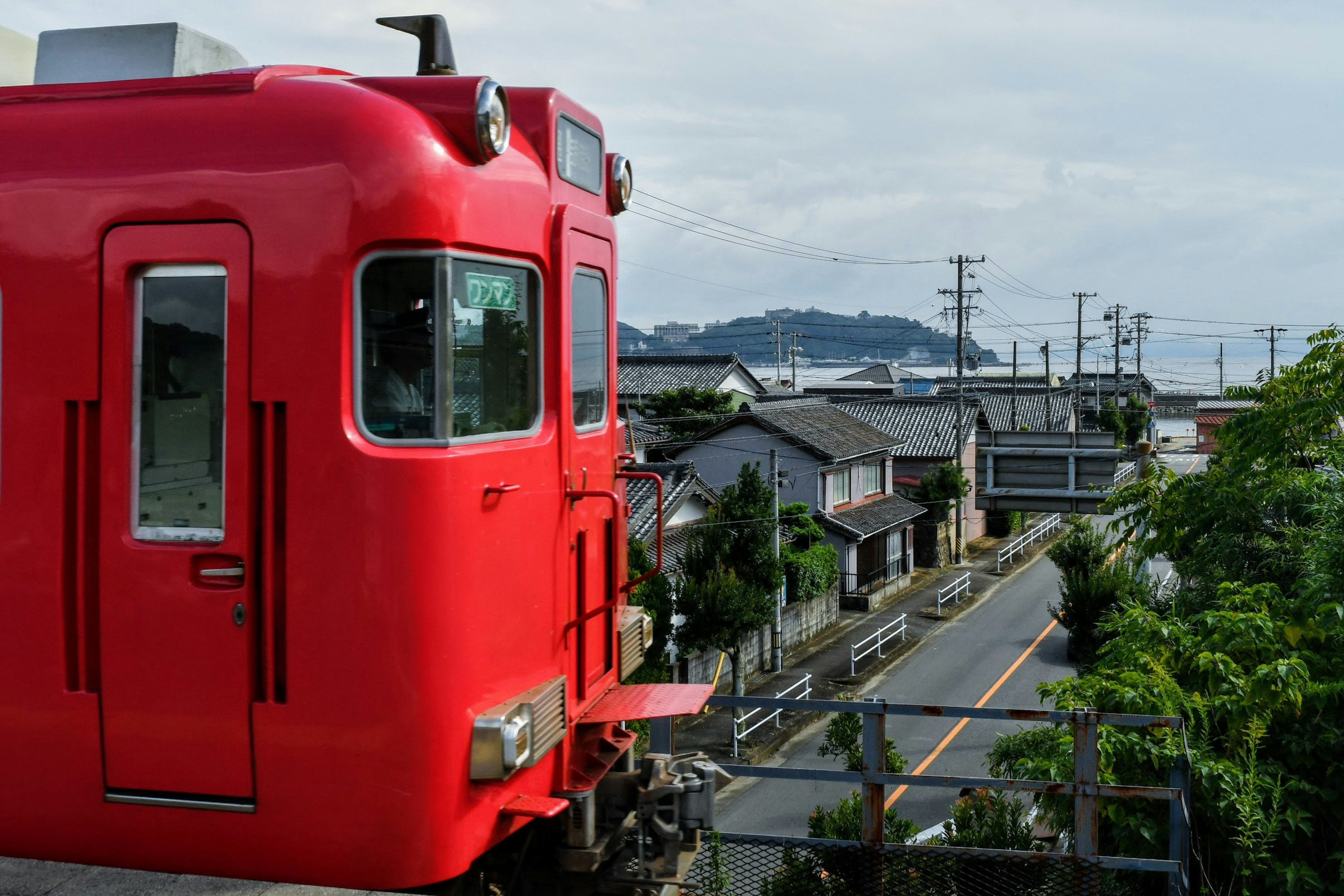 A red train overlooking a quiet town with houses and a distant landscape