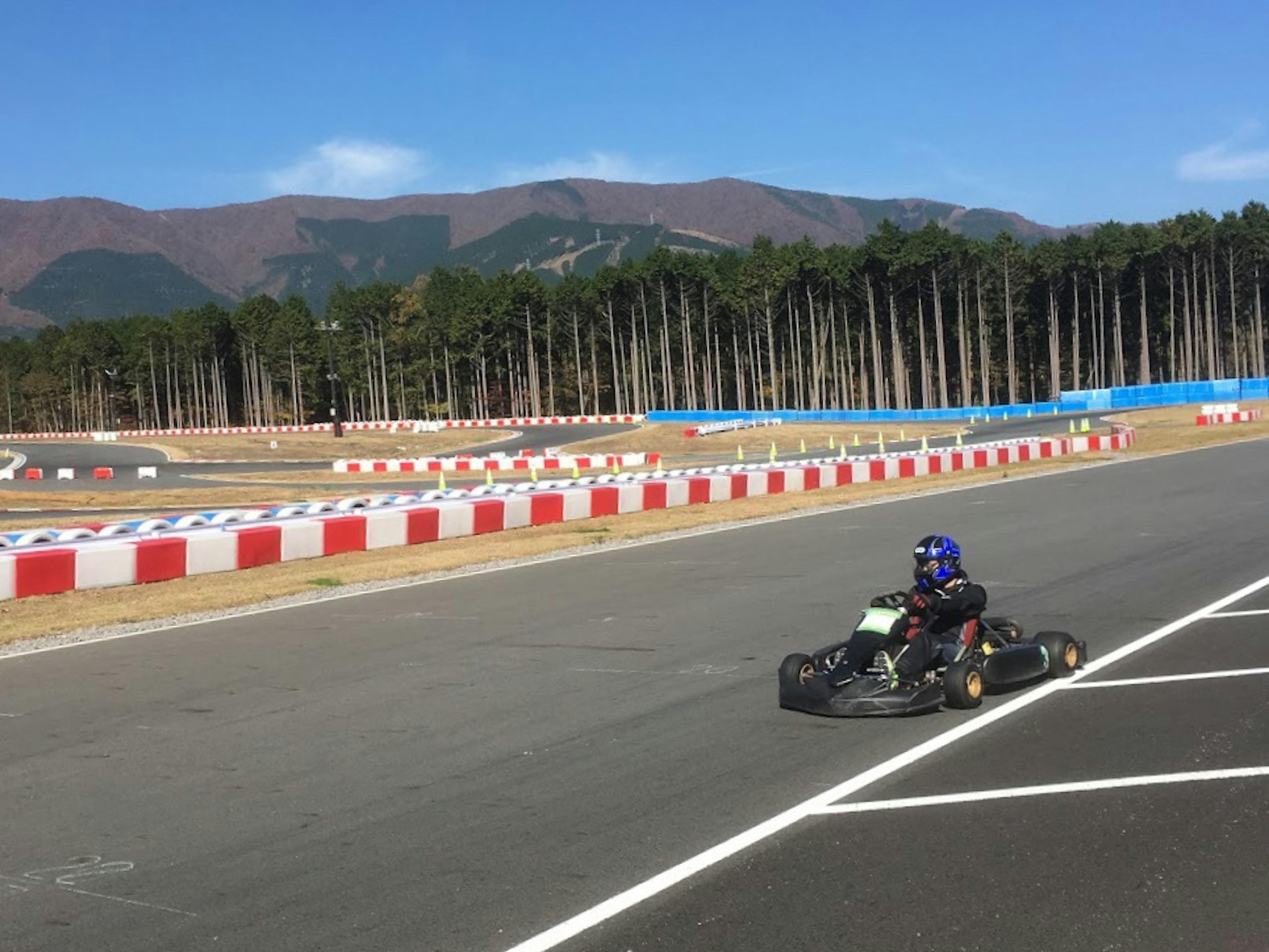 Go-kart racing on a circuit with blue sky and mountains in the background