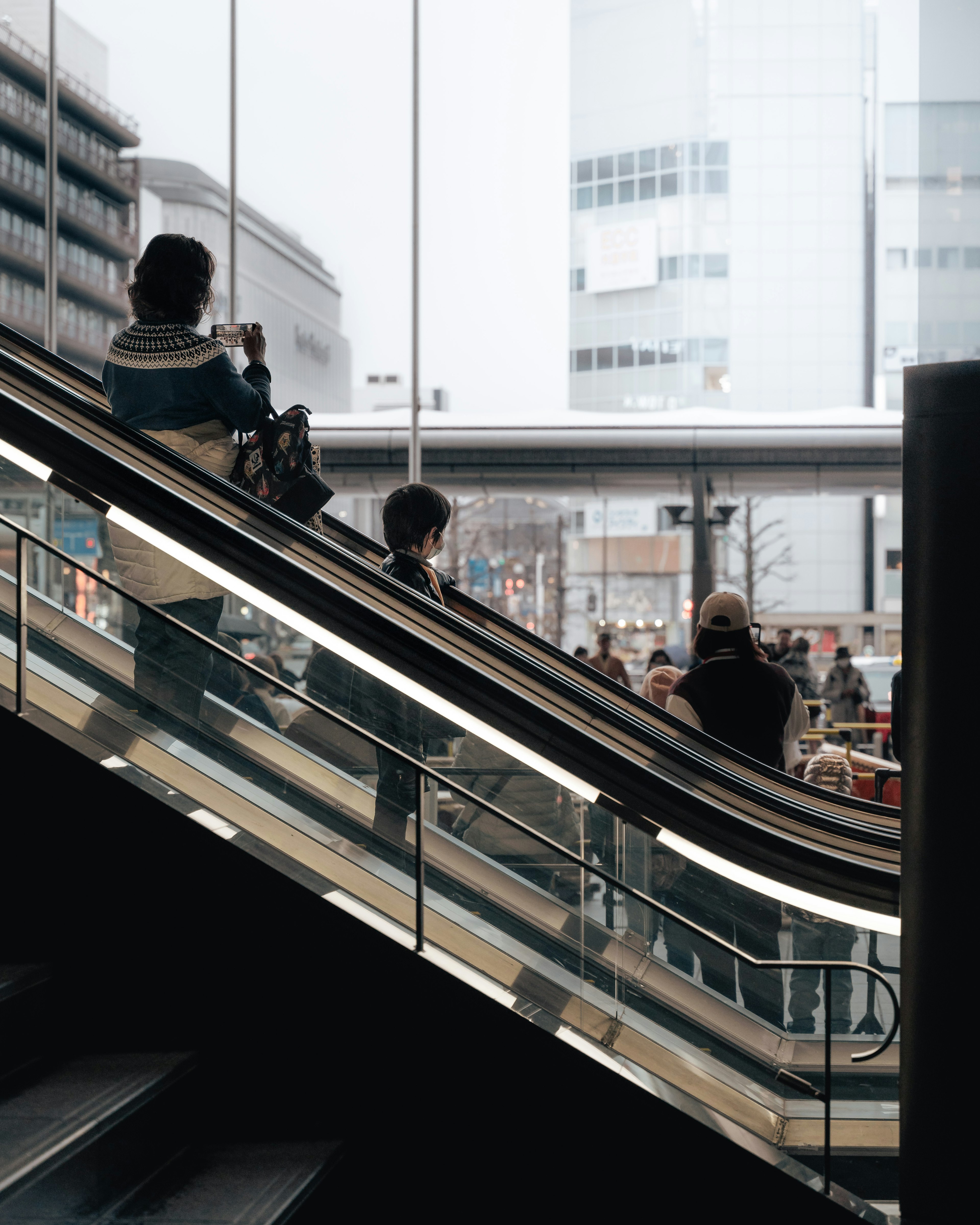 People using an escalator with a cityscape in the background