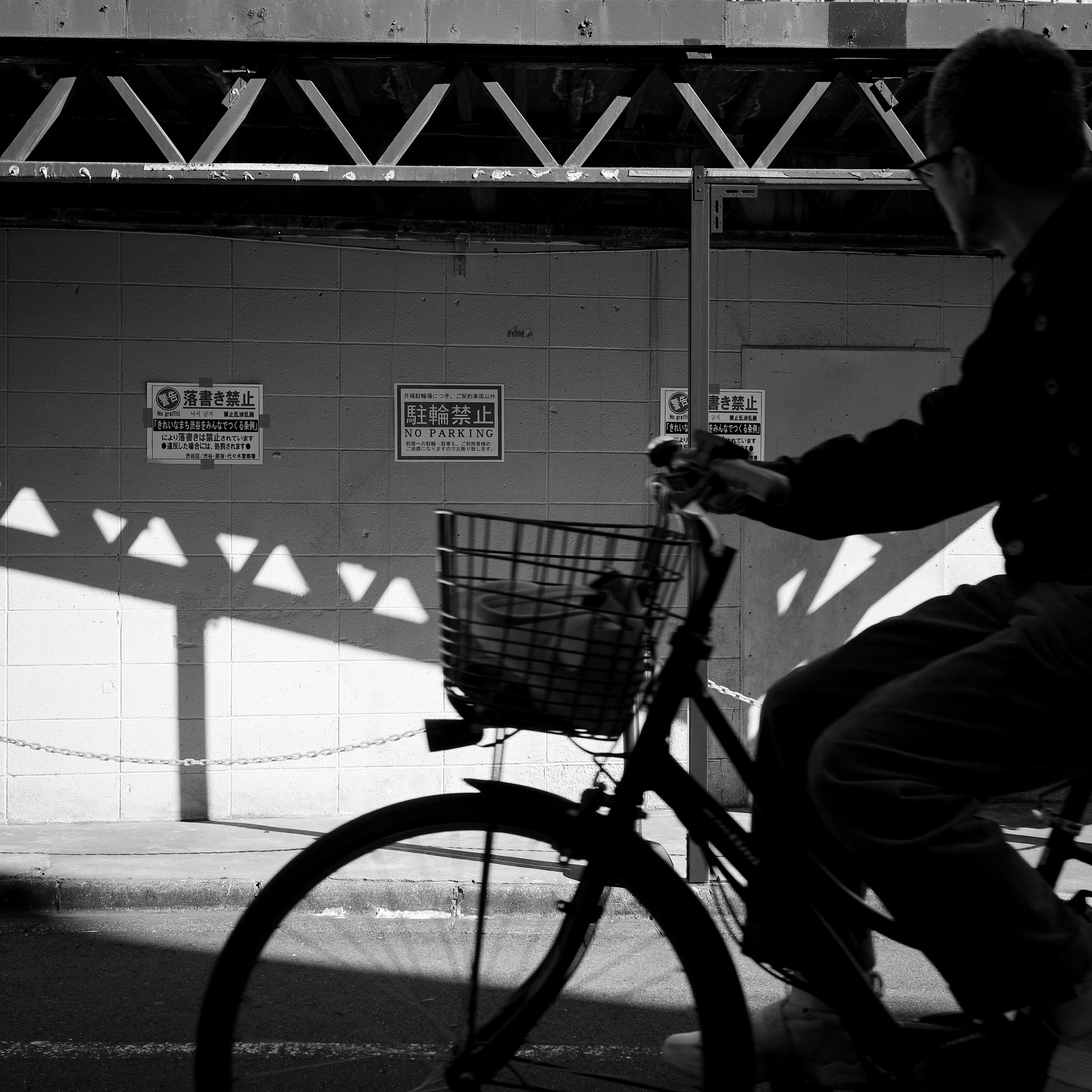 Imagen en blanco y negro de una persona montando una bicicleta con sombras de fondo