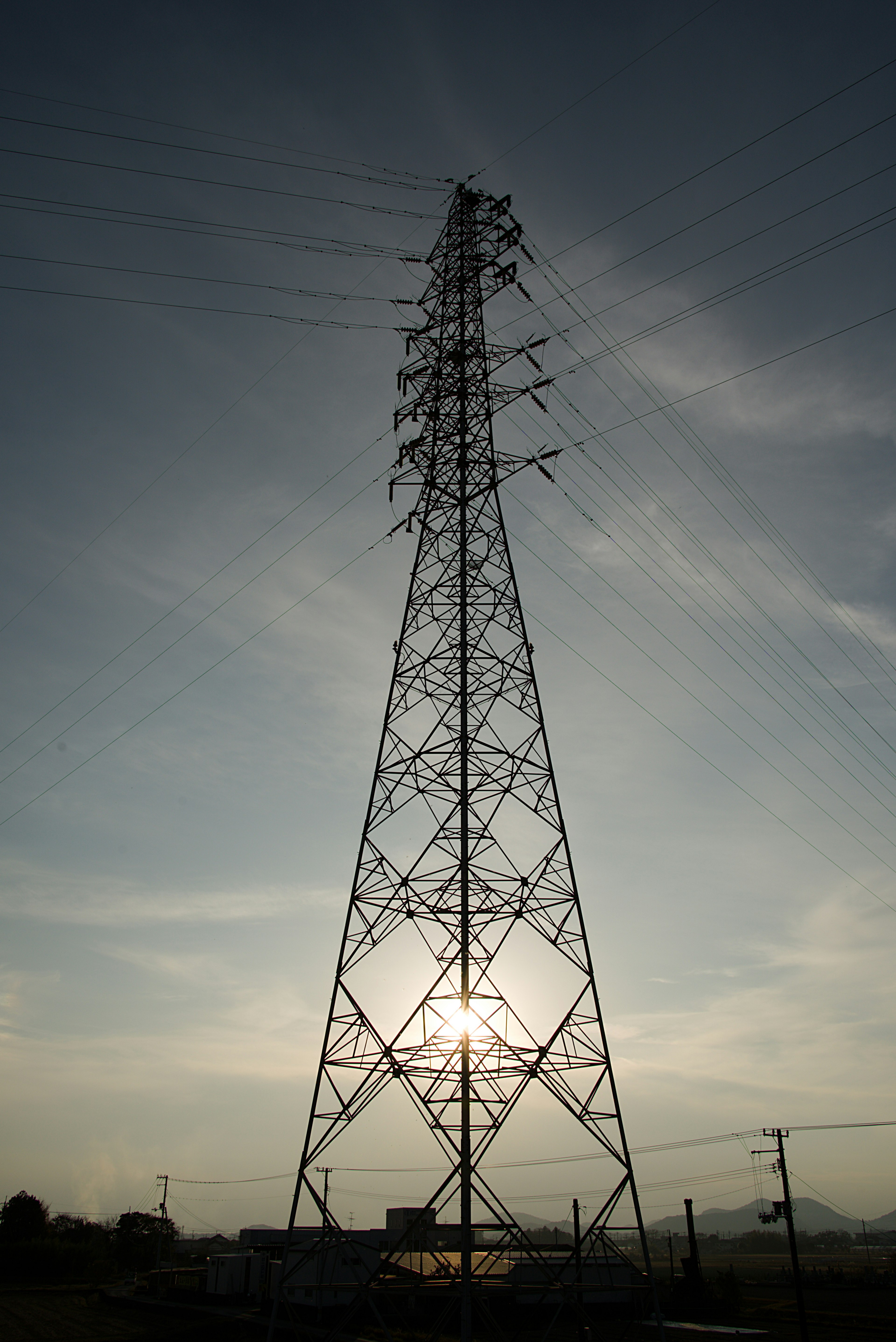 夕日を背景にした高圧電線タワーのシルエット