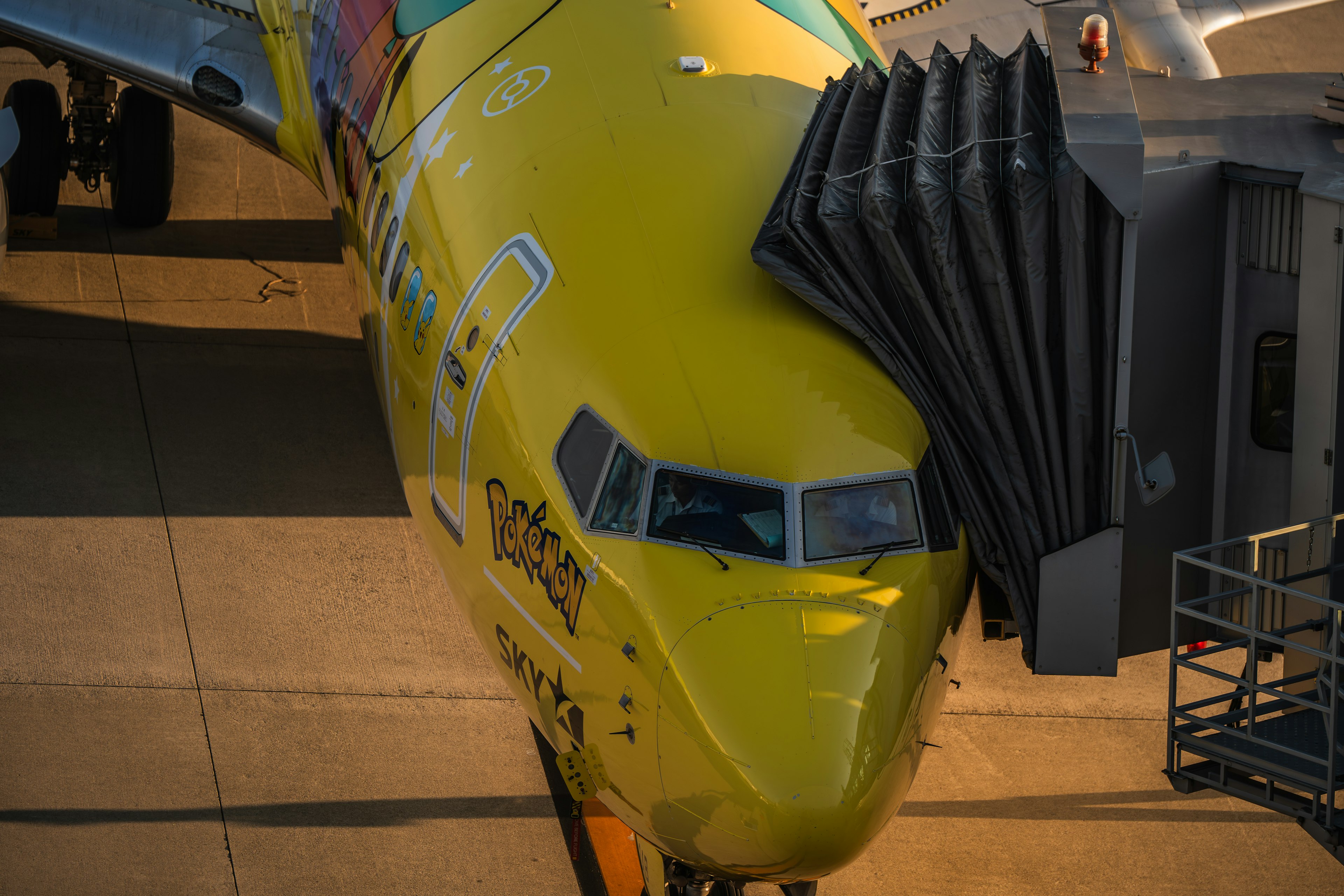 Vue de face d'un avion jaune à l'aéroport avec passerelle d'embarquement