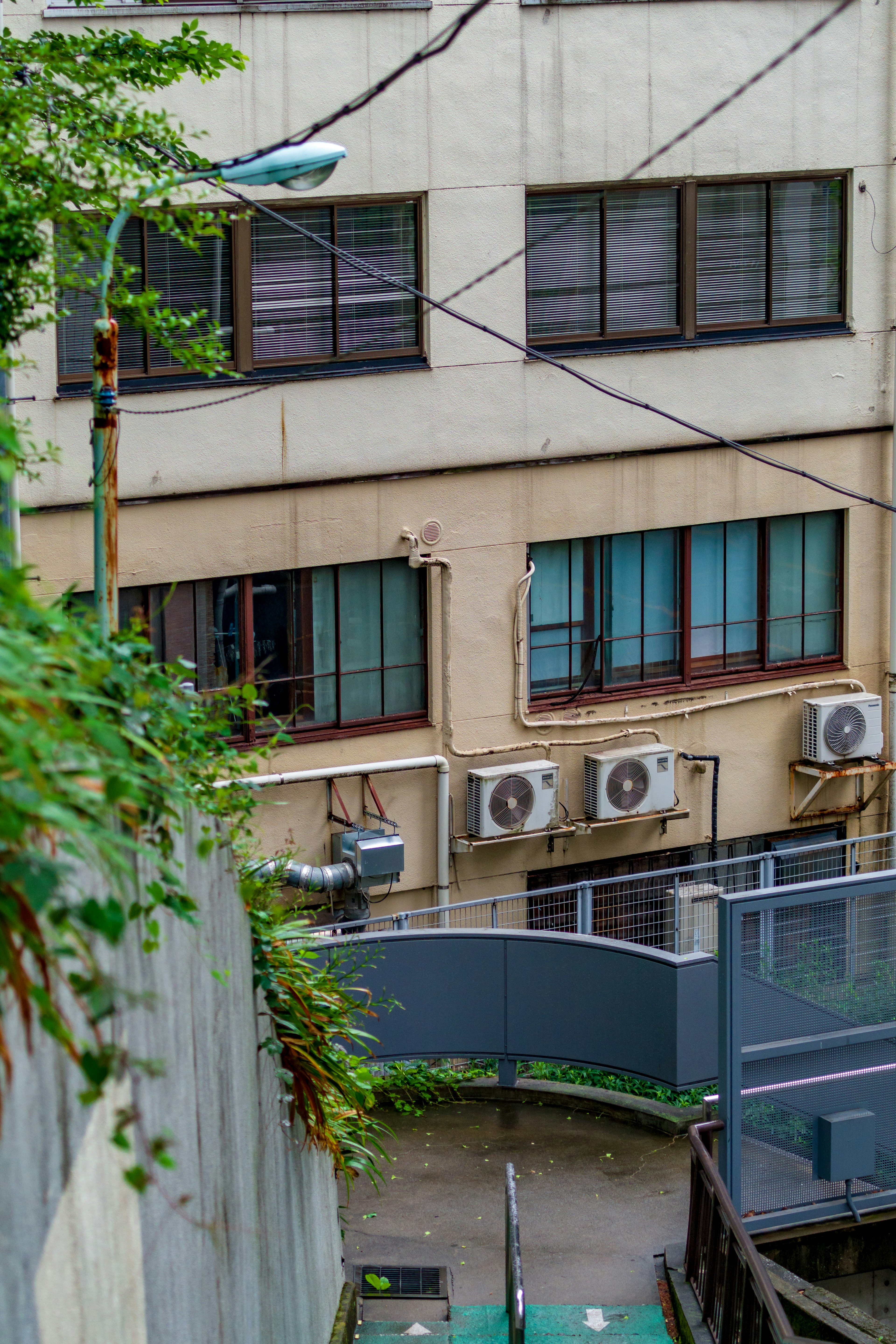 Vue extérieure d'un bâtiment avec fenêtres et unités de climatisation dans une ruelle étroite