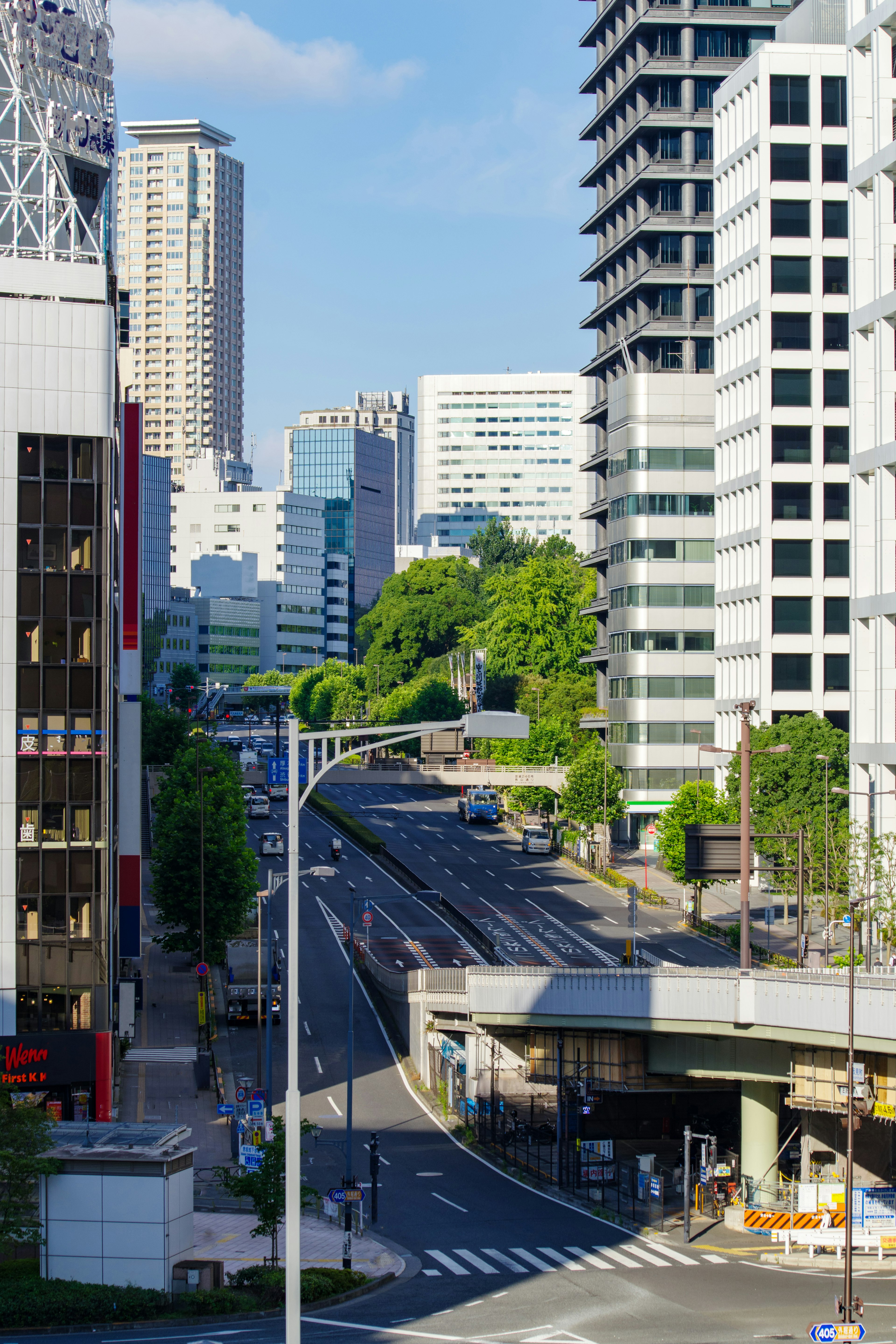 Khung cảnh đường chân trời Tokyo với những tòa nhà cao và bầu trời xanh trong, có một con đường vắng vẻ