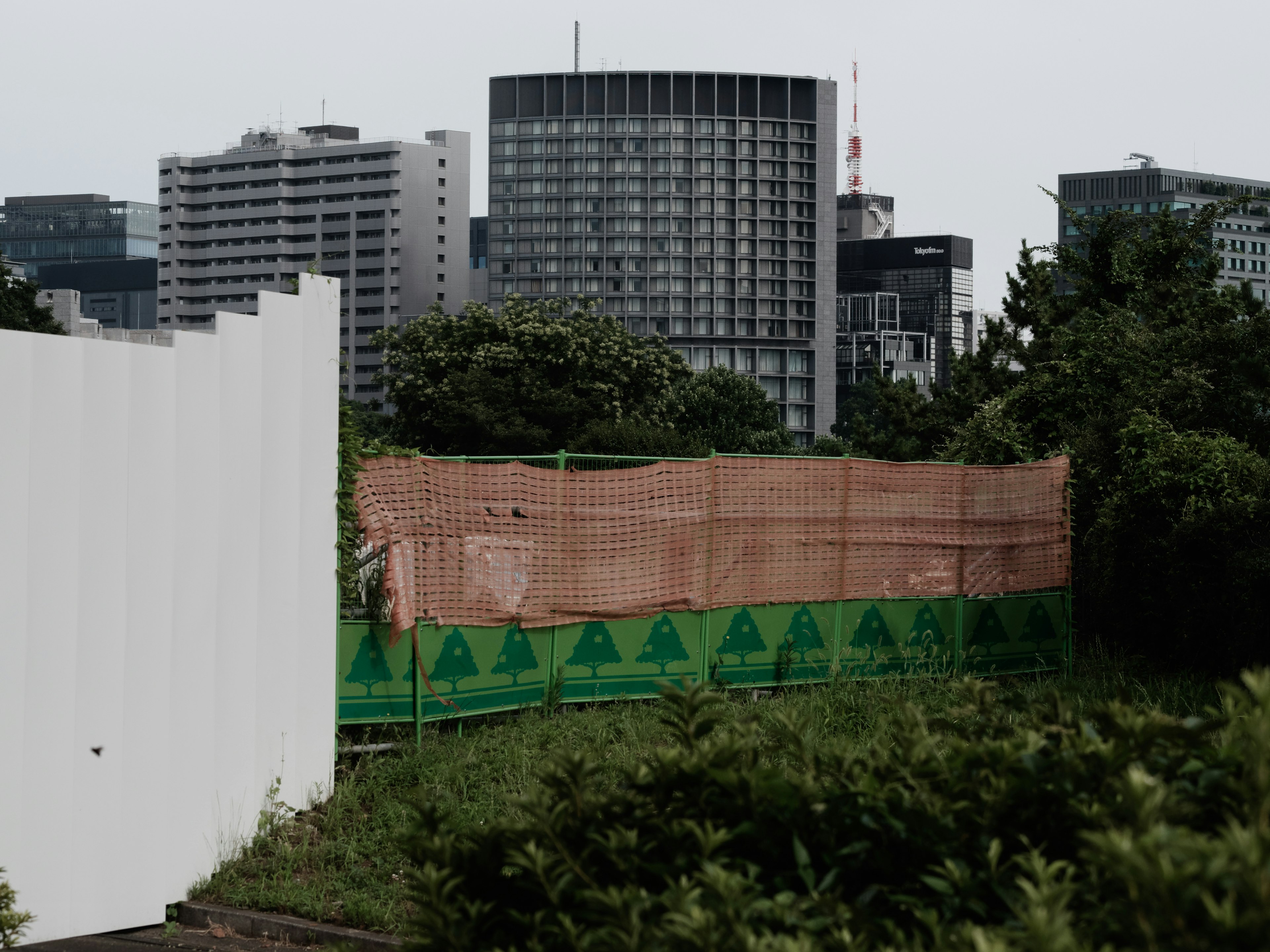 都市の高層ビルと工事現場のフェンスが見える風景