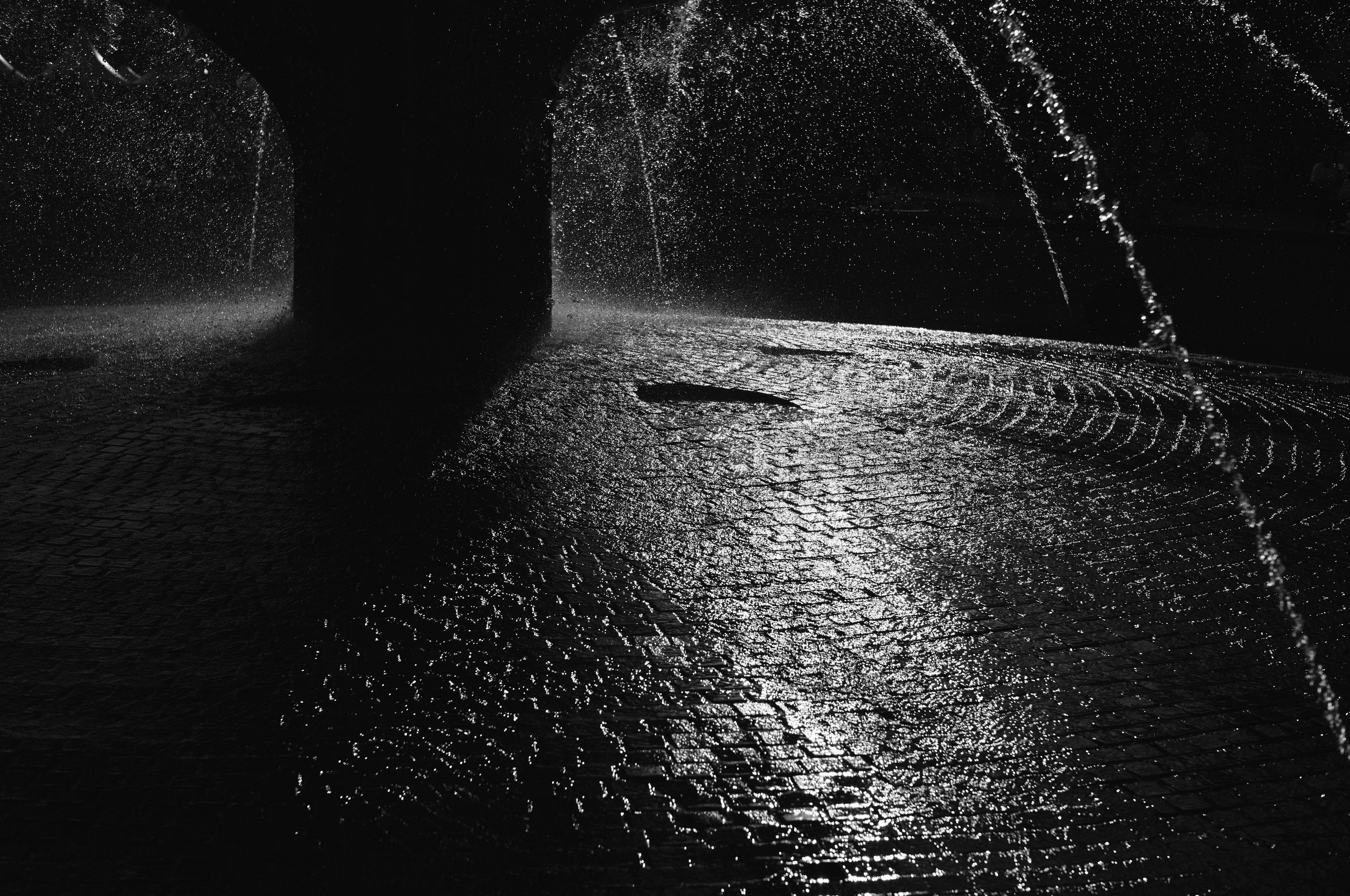 A tranquil scene with water fountains reflecting in a dark setting