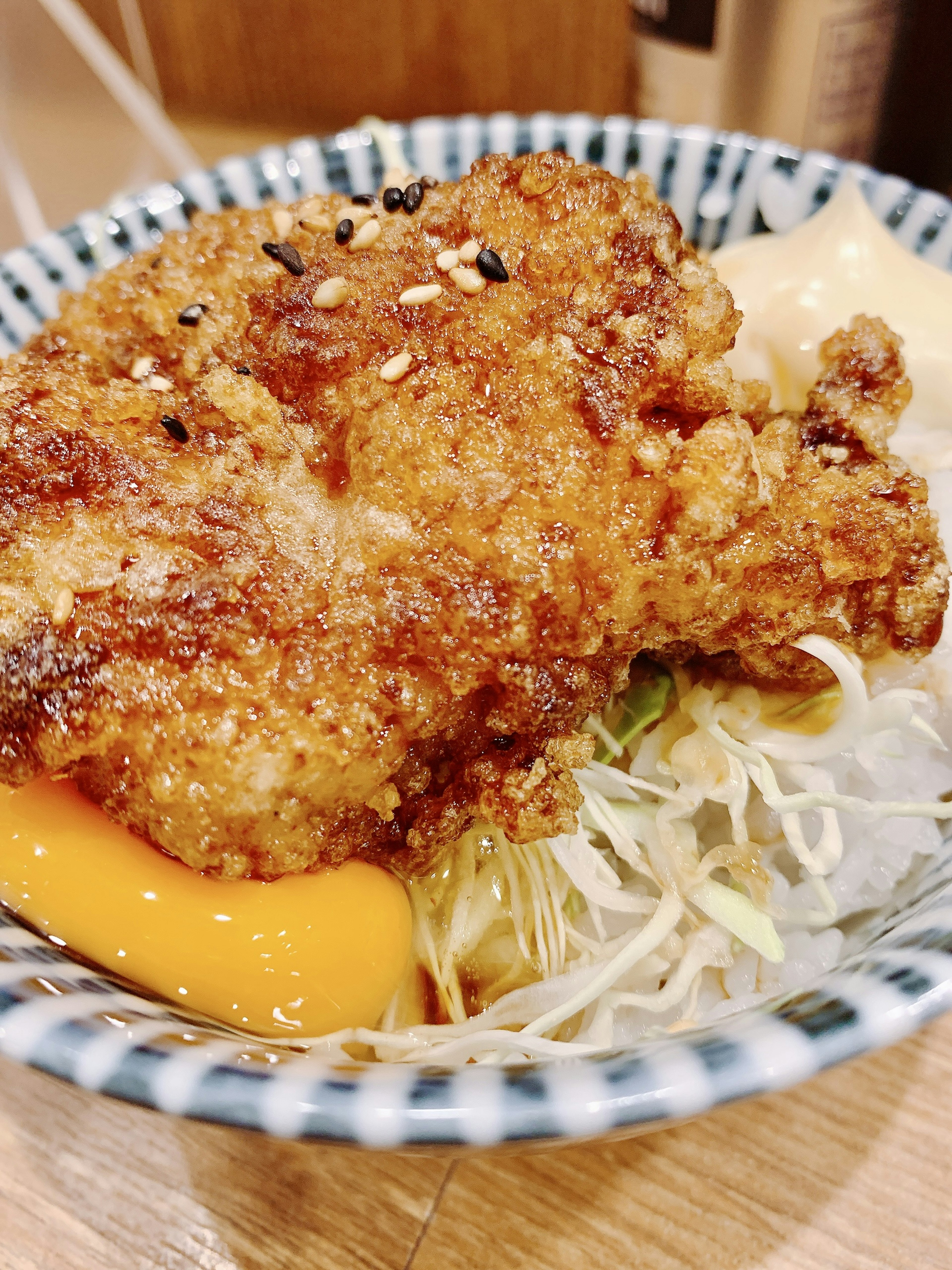 Crispy fried chicken served with shredded cabbage and a slice of egg on a decorative blue and white bowl