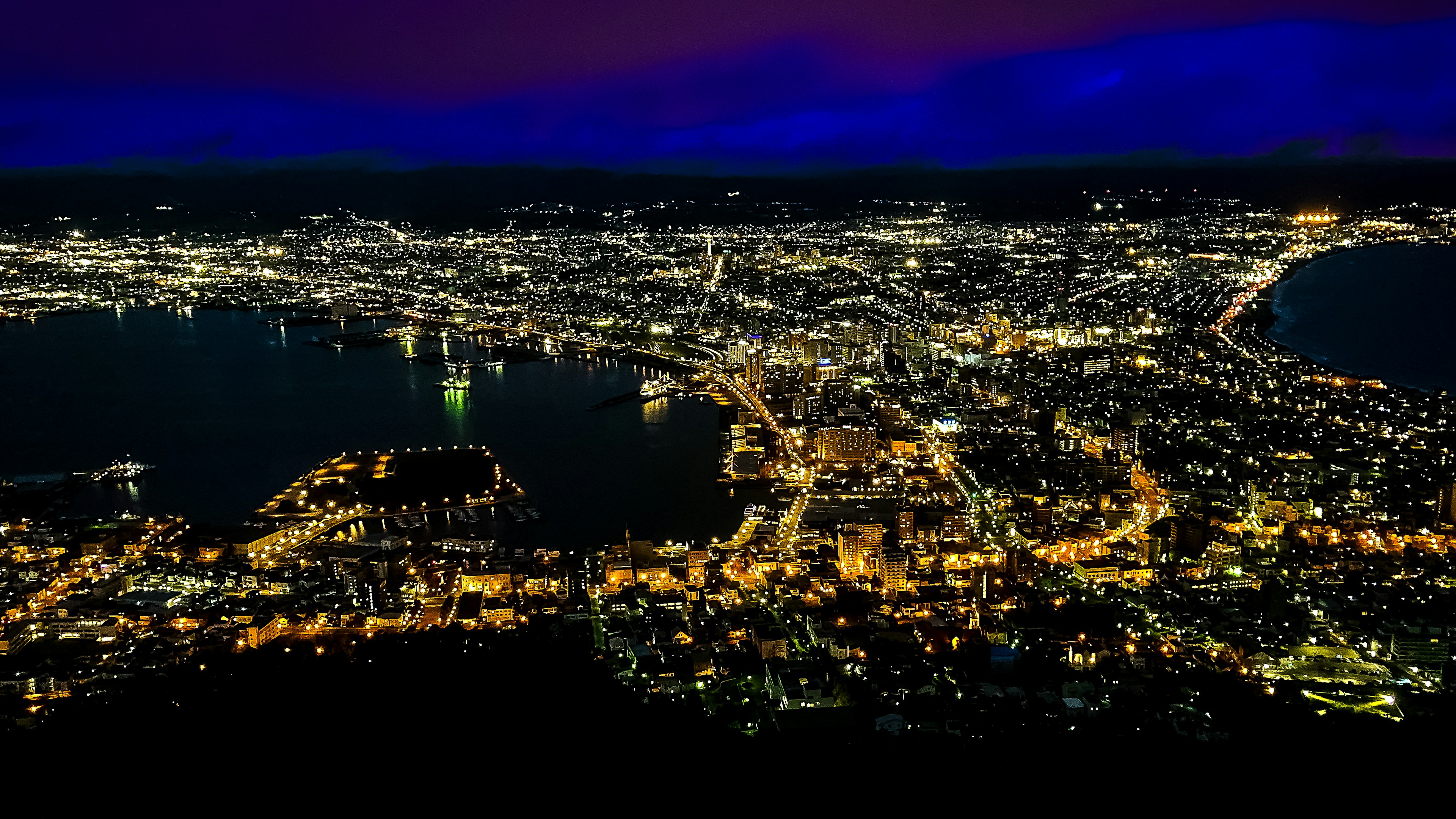 Night view of a cityscape illuminated with bright lights and harbor