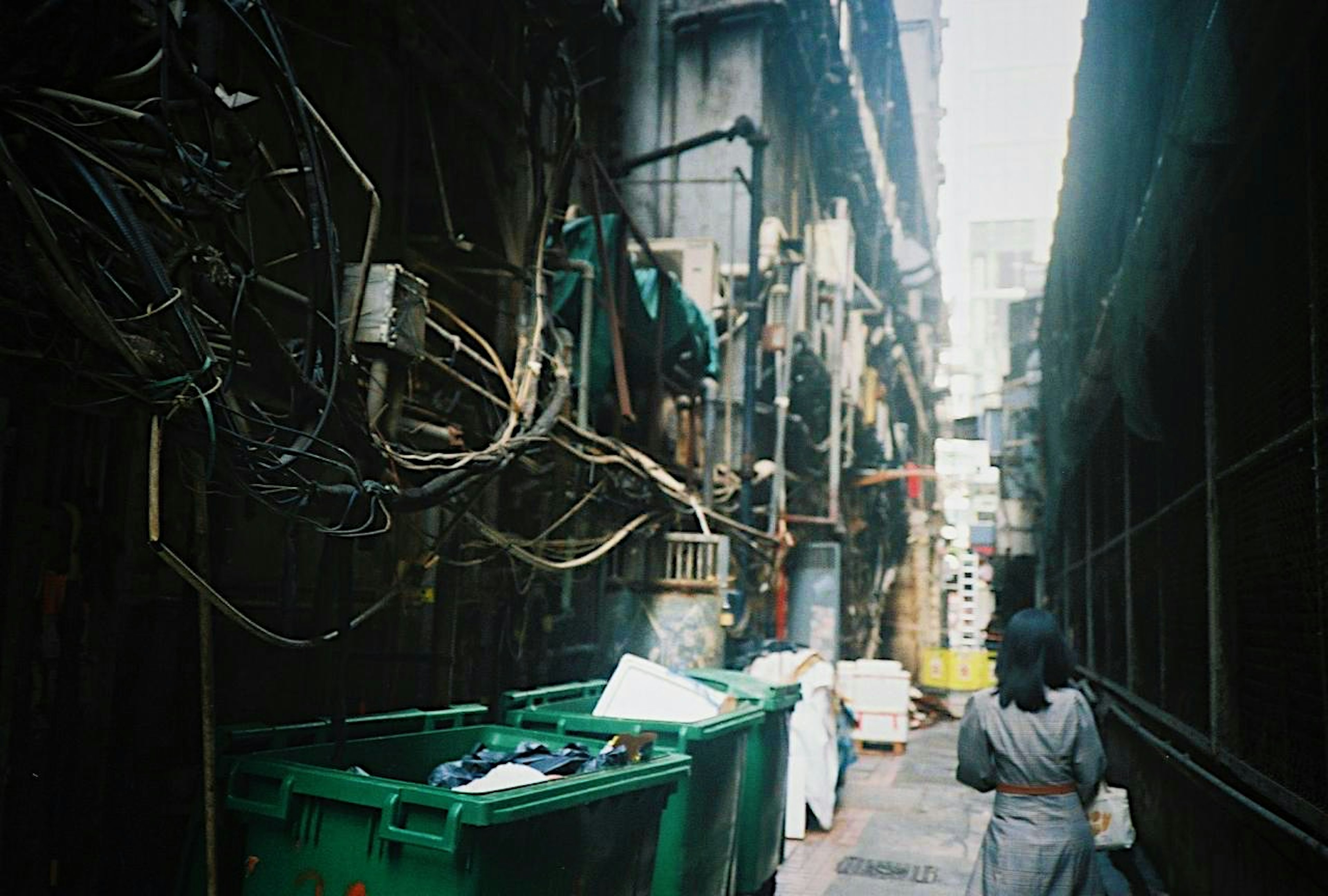 Narrow alley featuring trash bins and exposed wiring