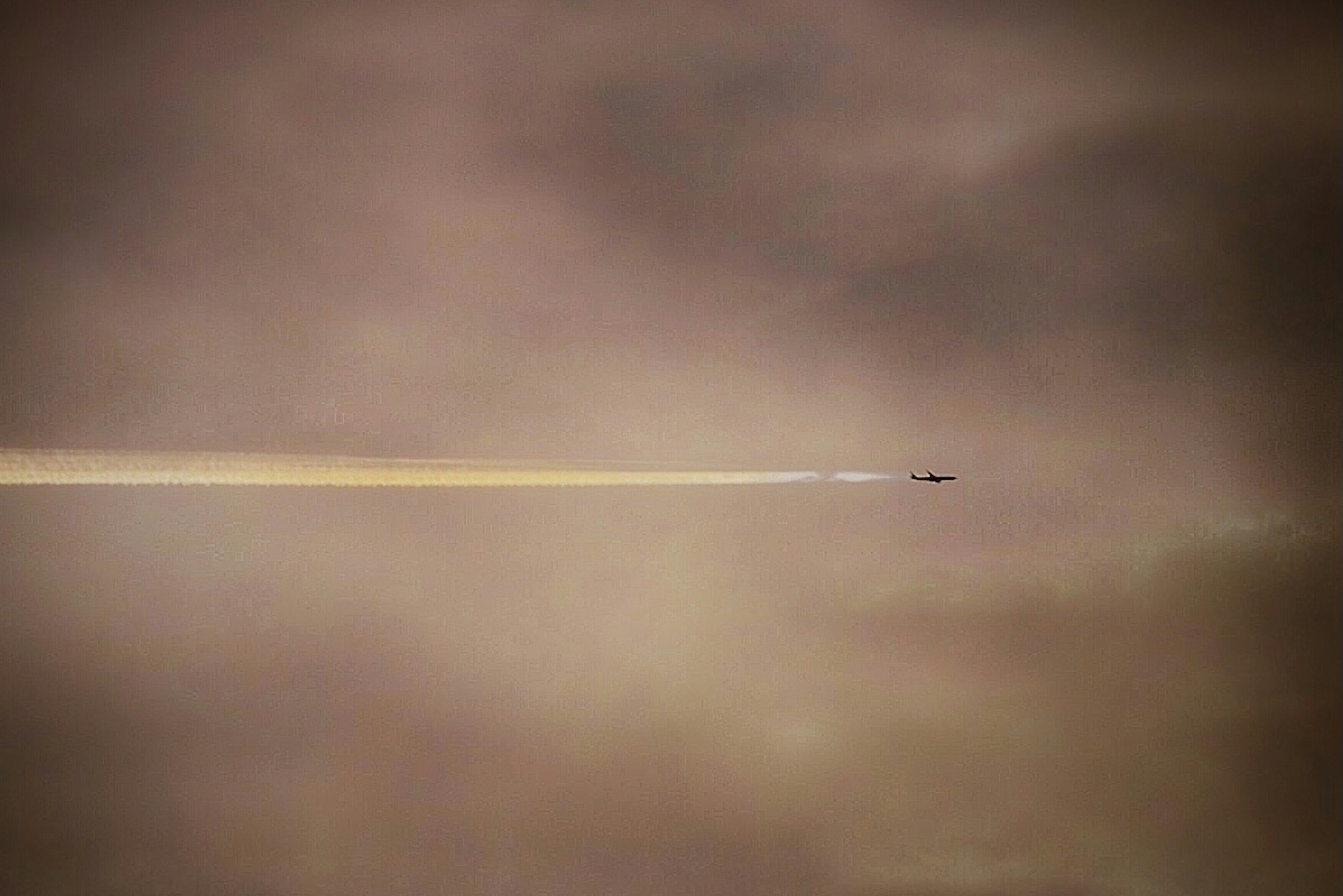 Avión volando entre nubes dejando un rastro detrás