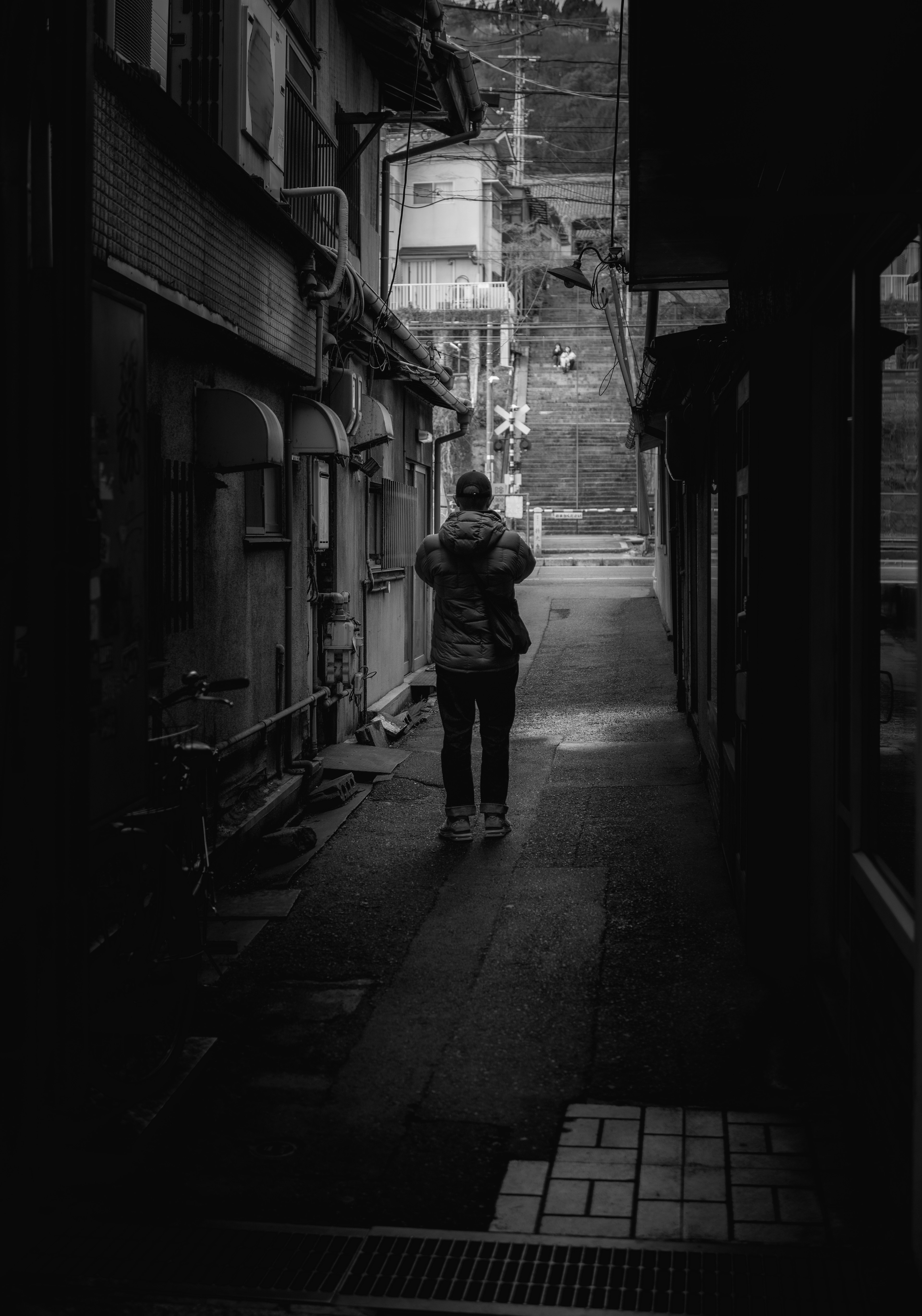 Photo en noir et blanc d'une personne marchant dans une ruelle étroite