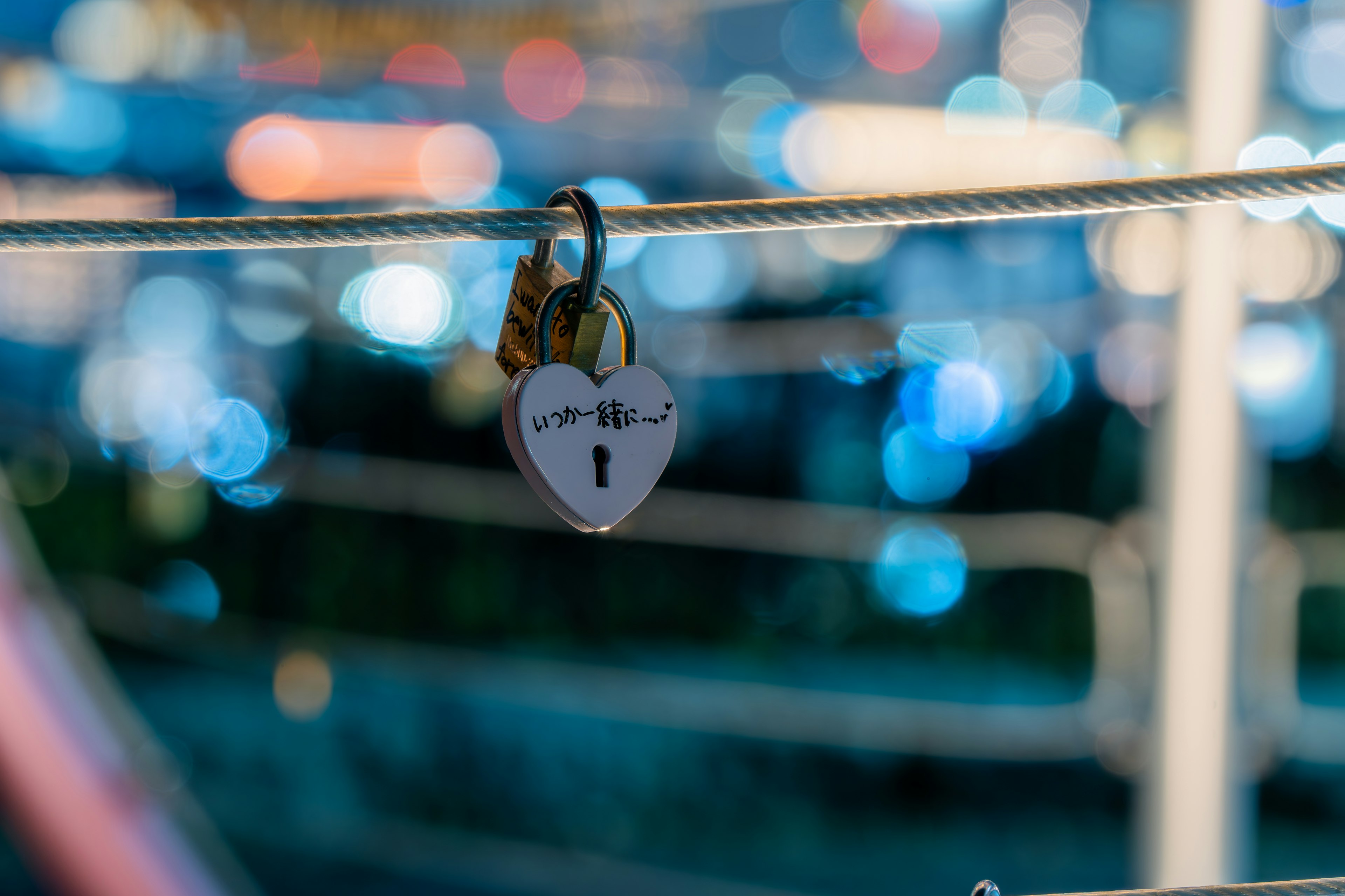 Heart-shaped padlock hanging on a rope with a blurred blue light background