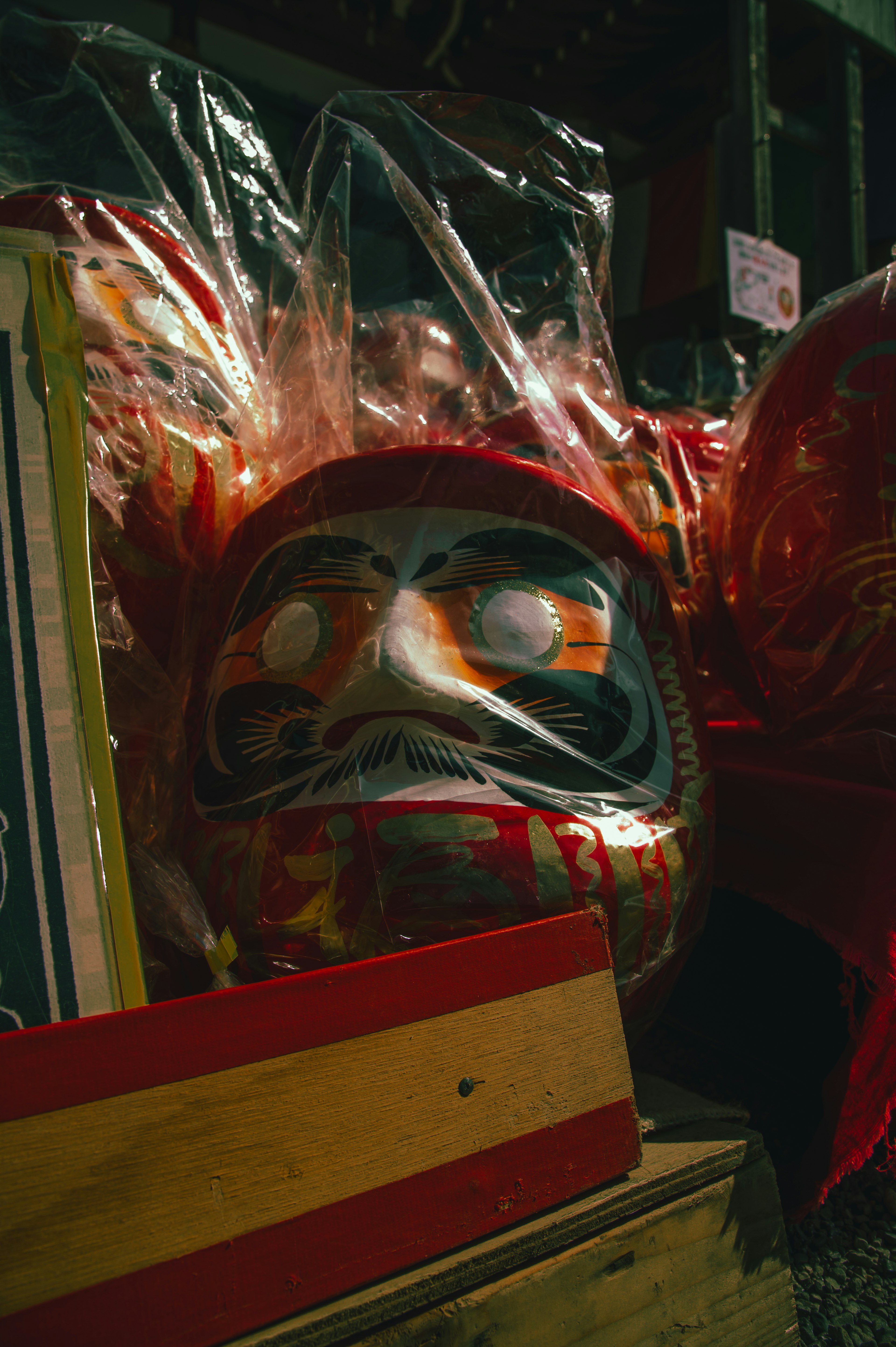 Traditional mask with red decorations wrapped in clear plastic