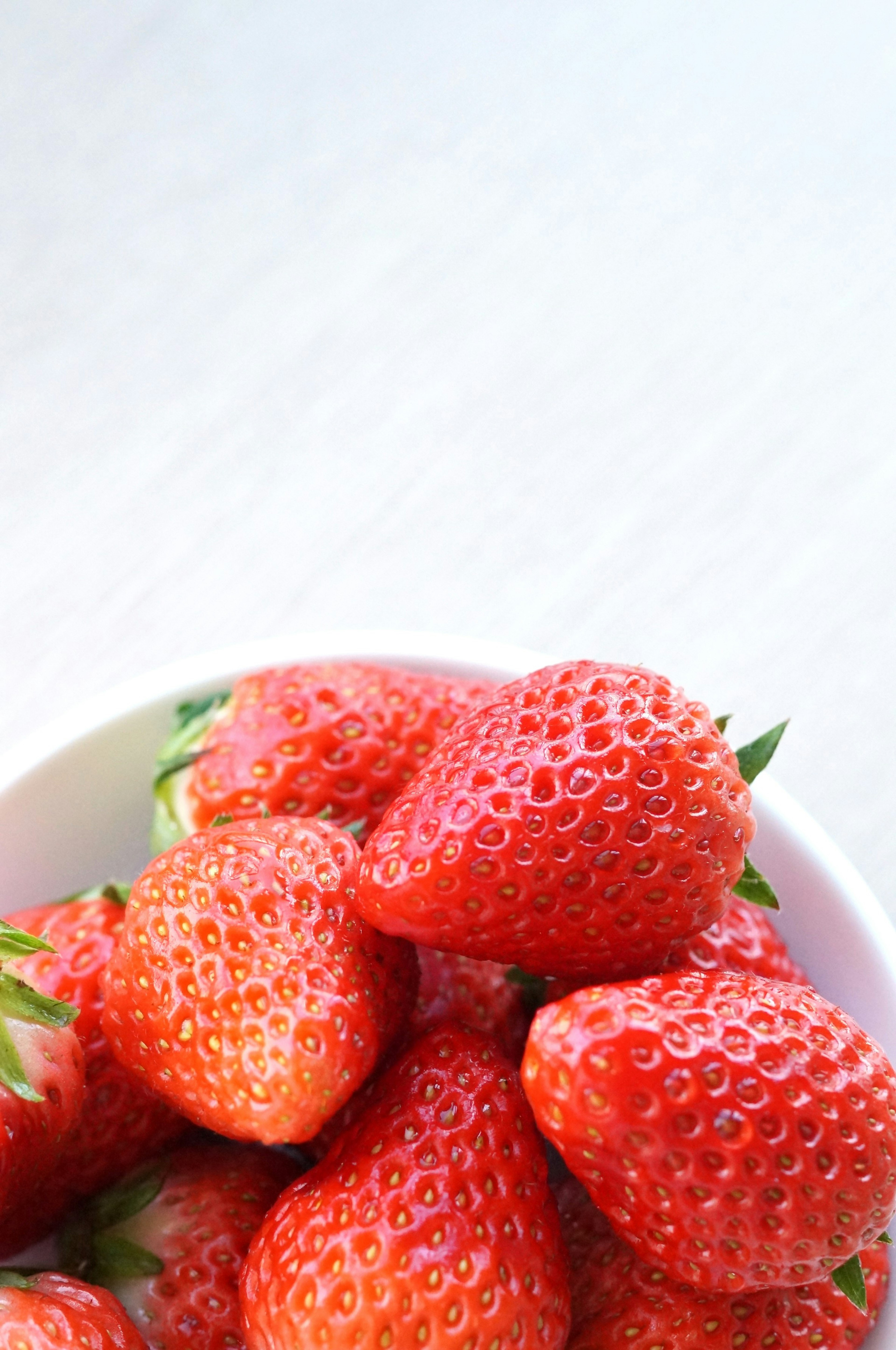 Fresh strawberries piled in a white bowl