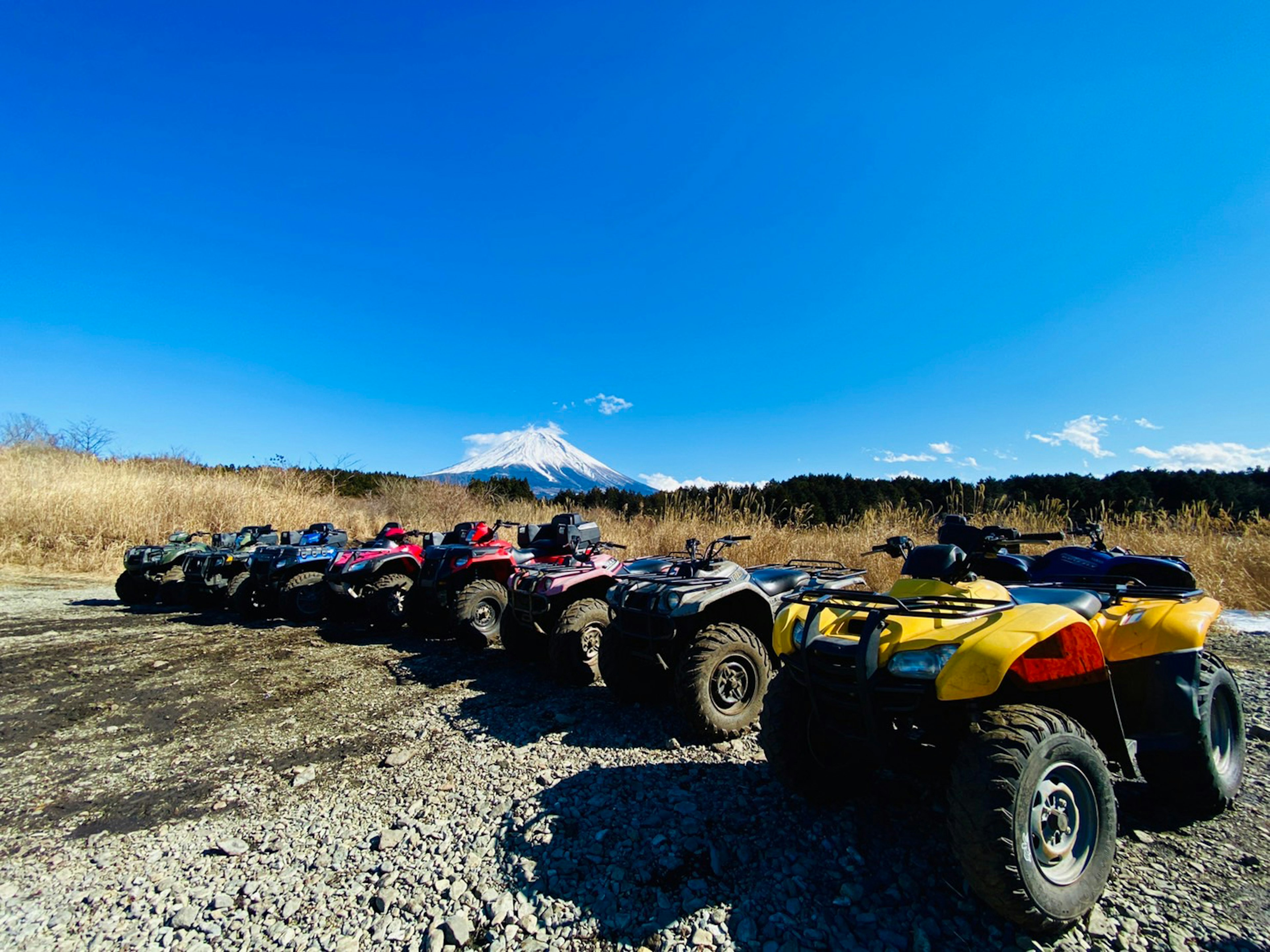 Row of ATVs under a blue sky with Mount Fuji in the background