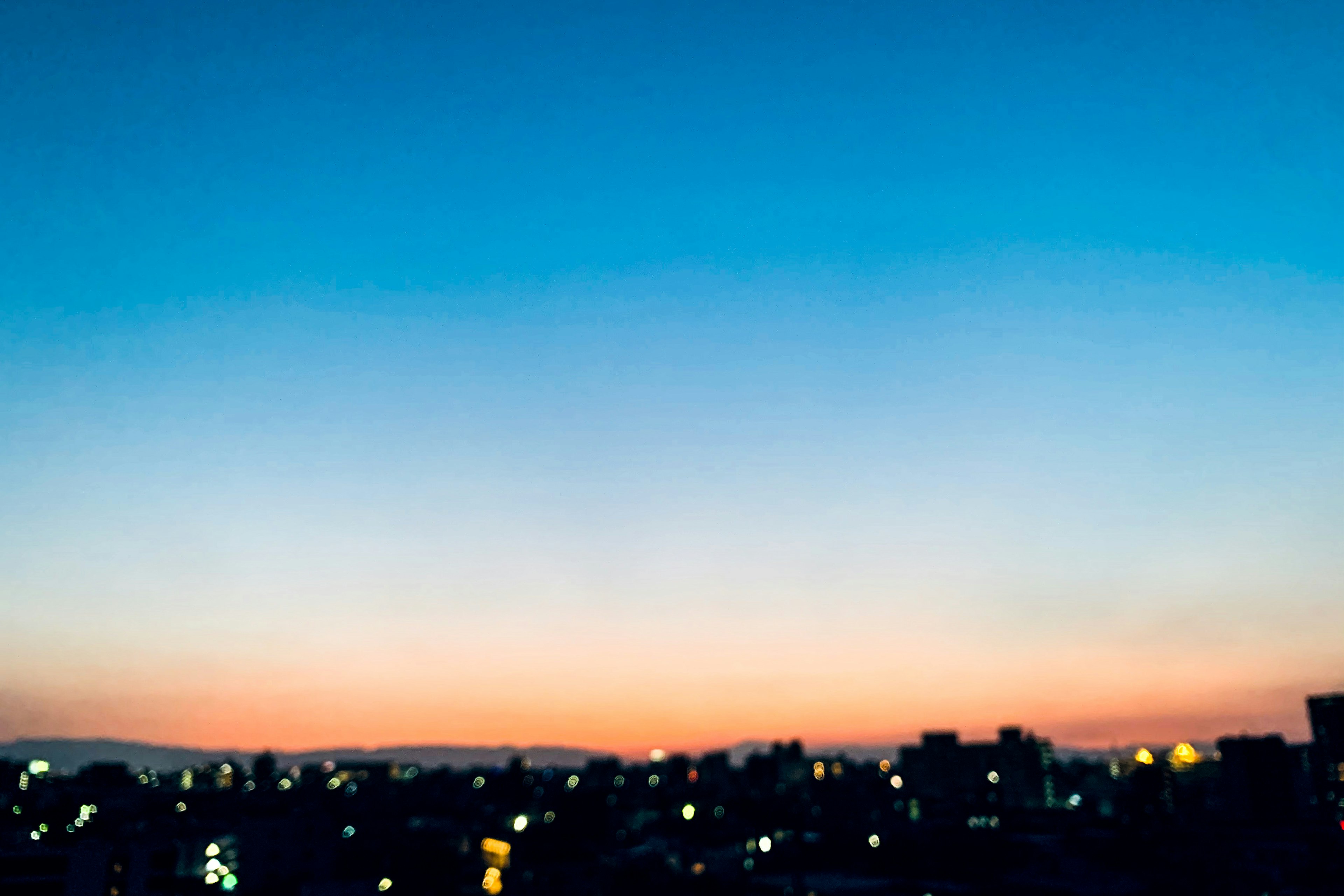 Verlaufs Himmel mit blauen und orangefarbenen Tönen und Stadtlichtern