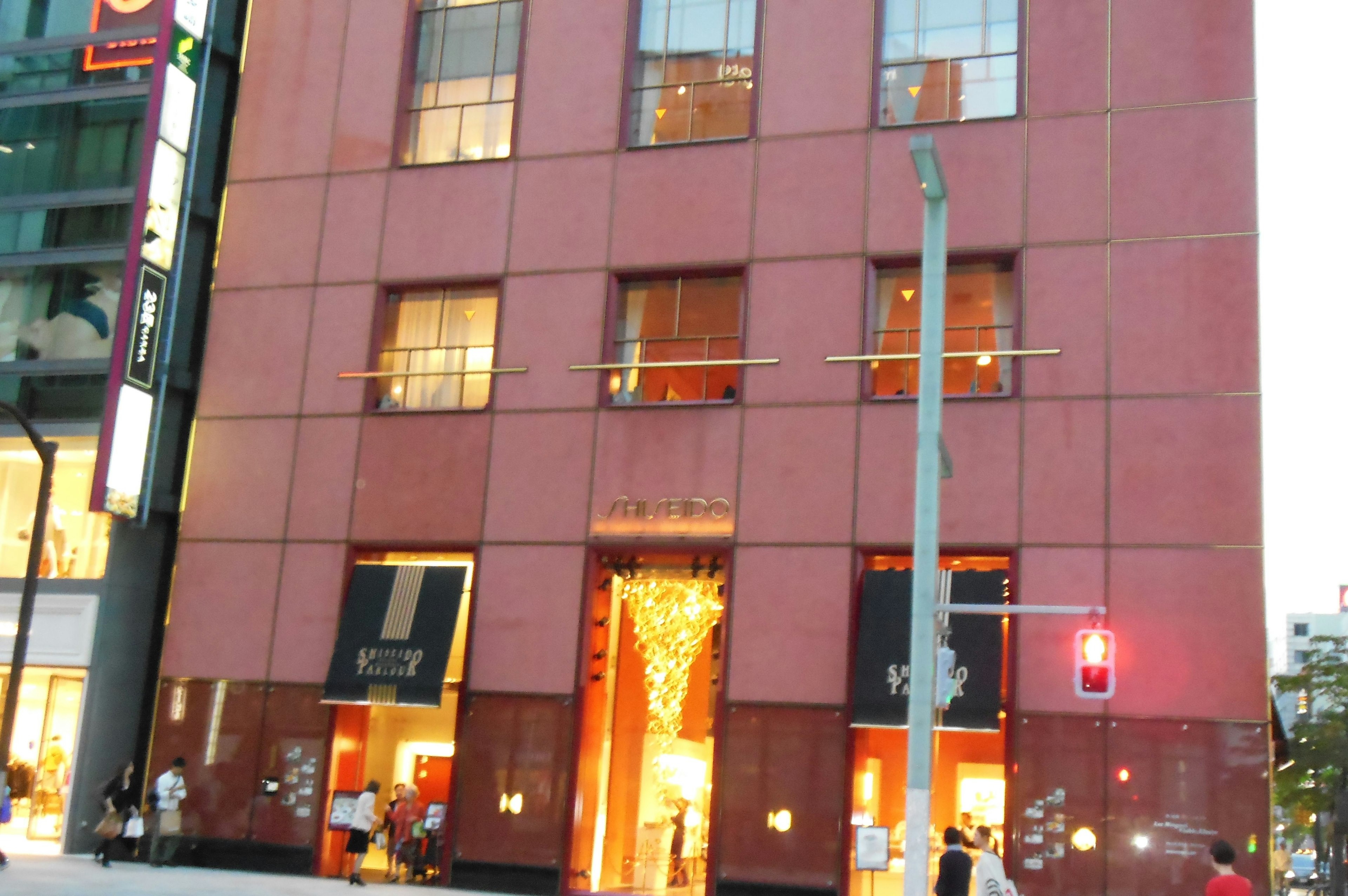 Modern building with red exterior featuring bright windows and a luxurious entrance