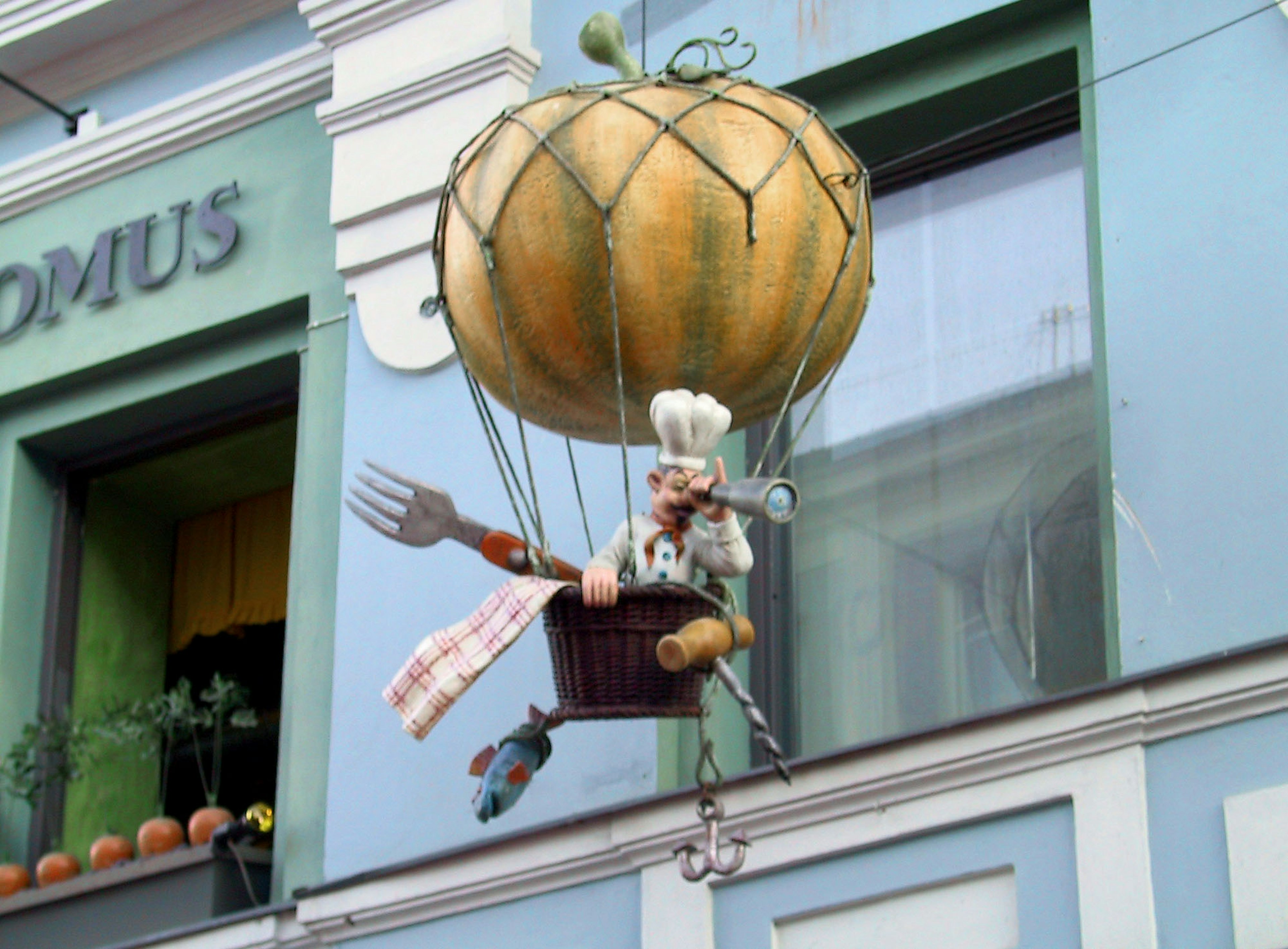 Un panneau fantaisiste représentant une figurine de chef dans une montgolfière en forme de citrouille