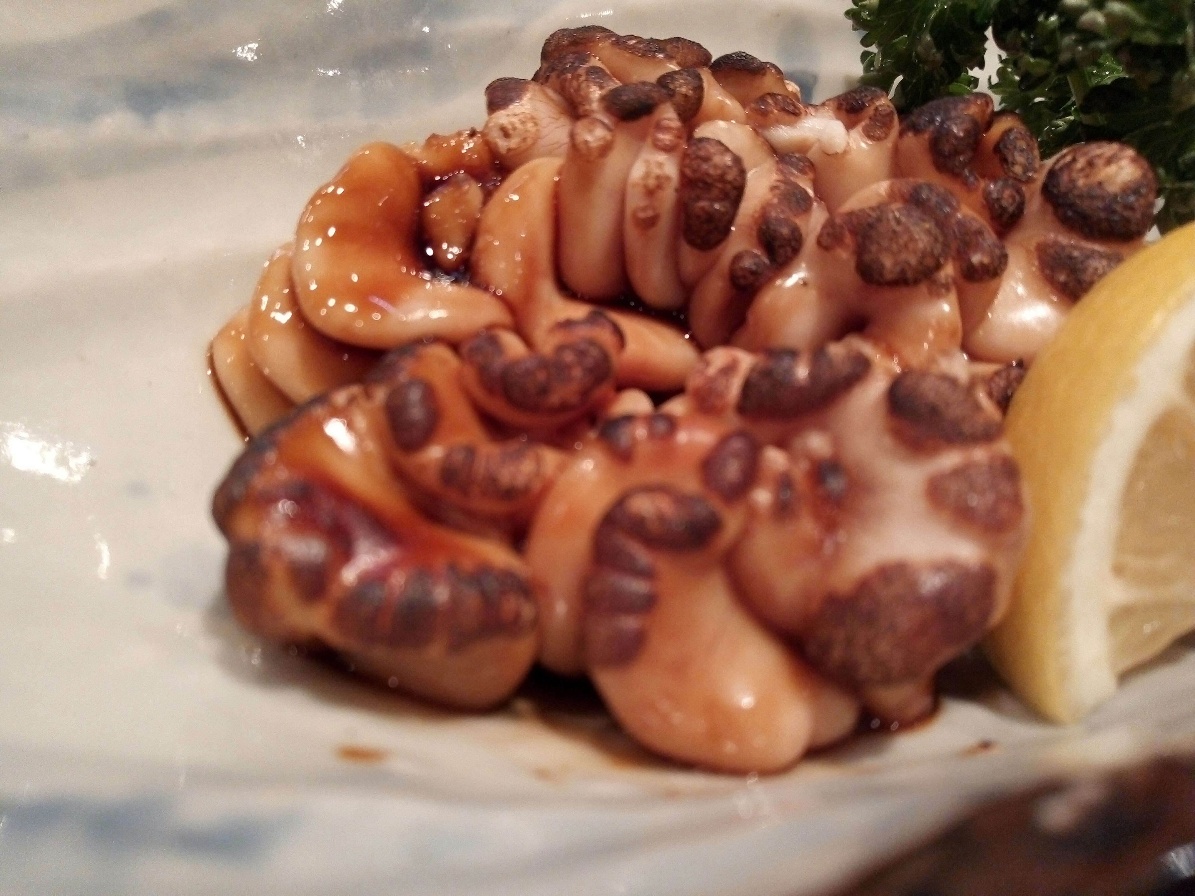 A delicious octopus dish served on a plate with a slice of lemon