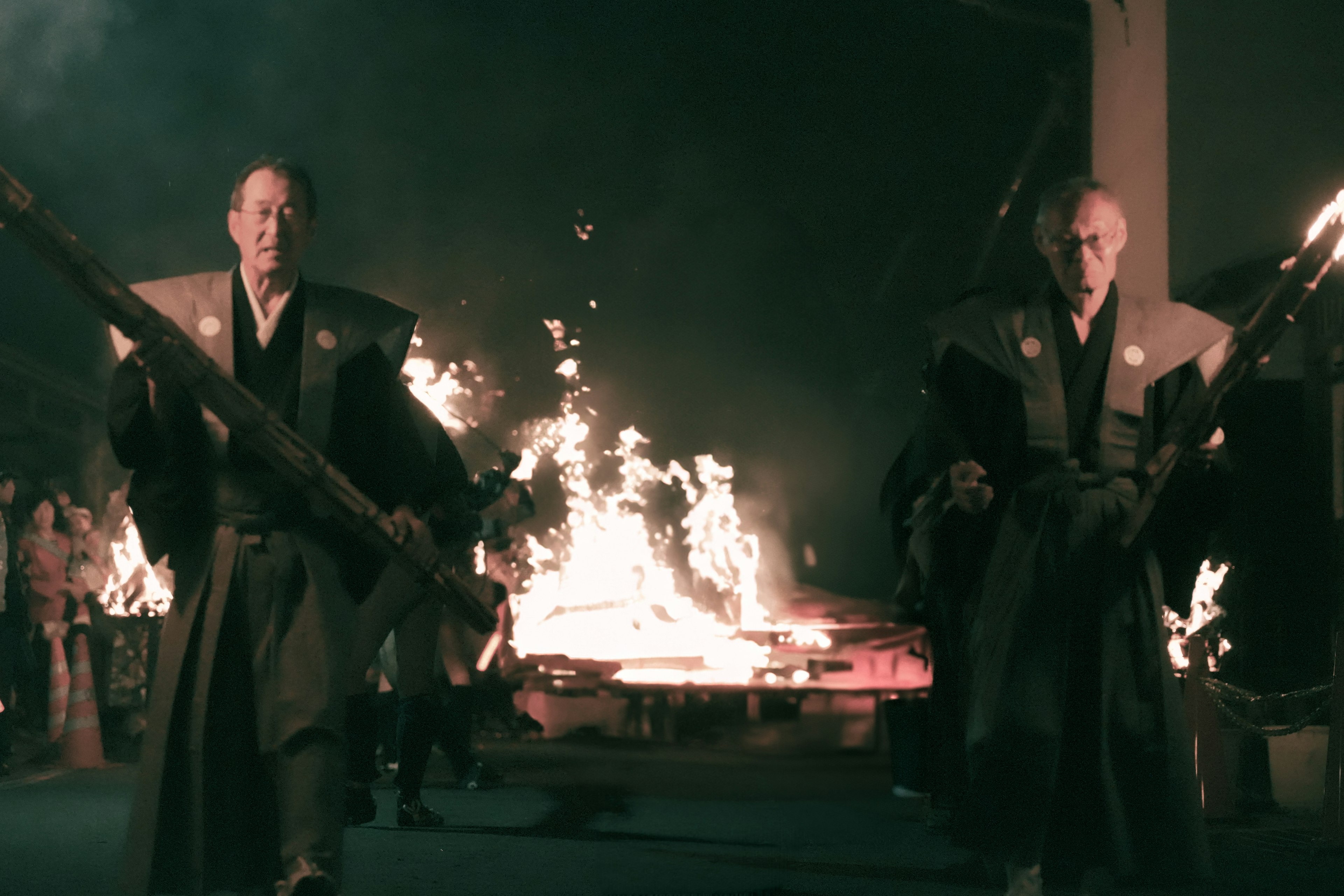 Two warriors with large weapons walking through flames