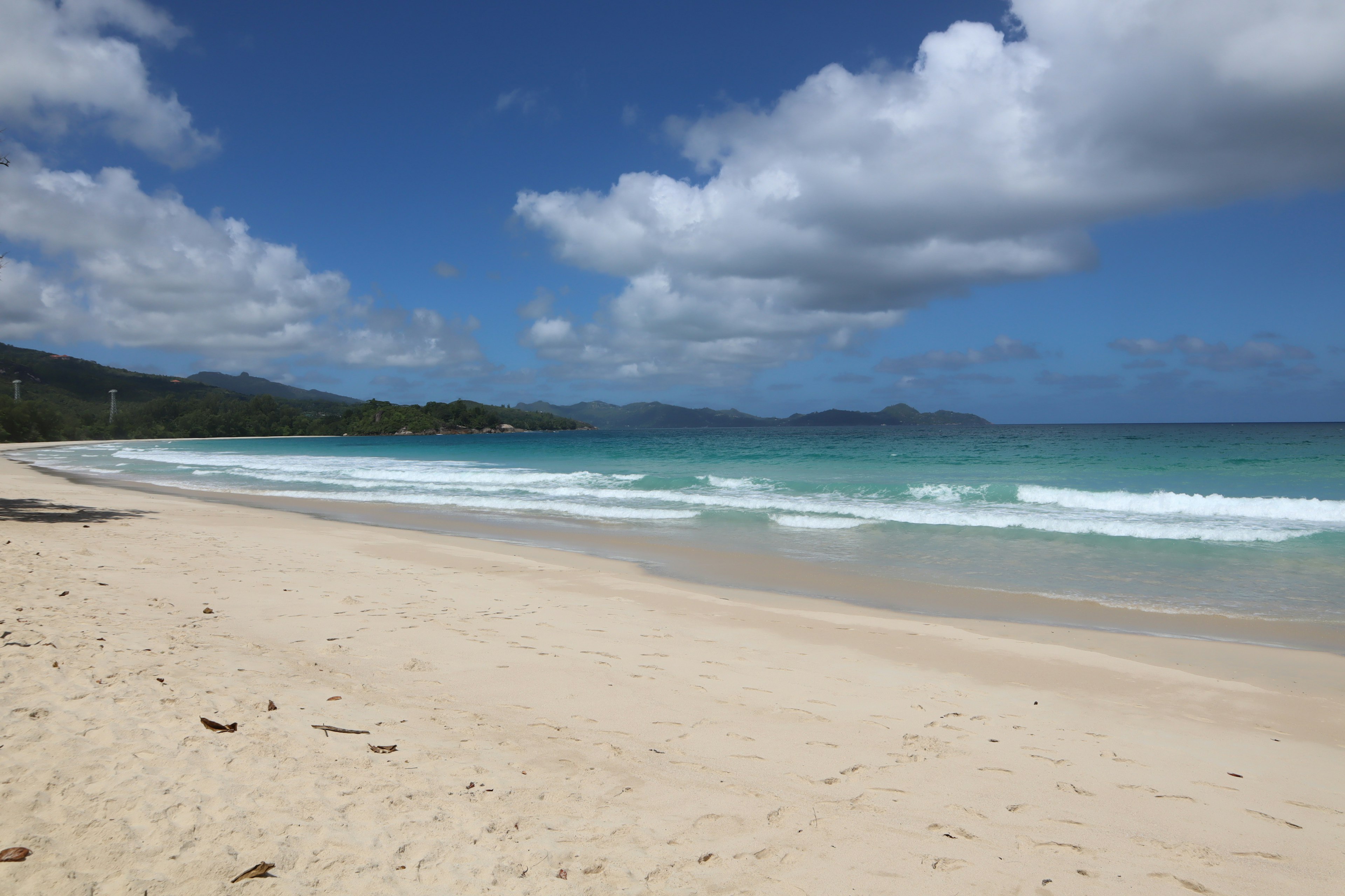 ทิวทัศน์ชายหาดที่มีน้ำสีฟ้าและทรายขาว